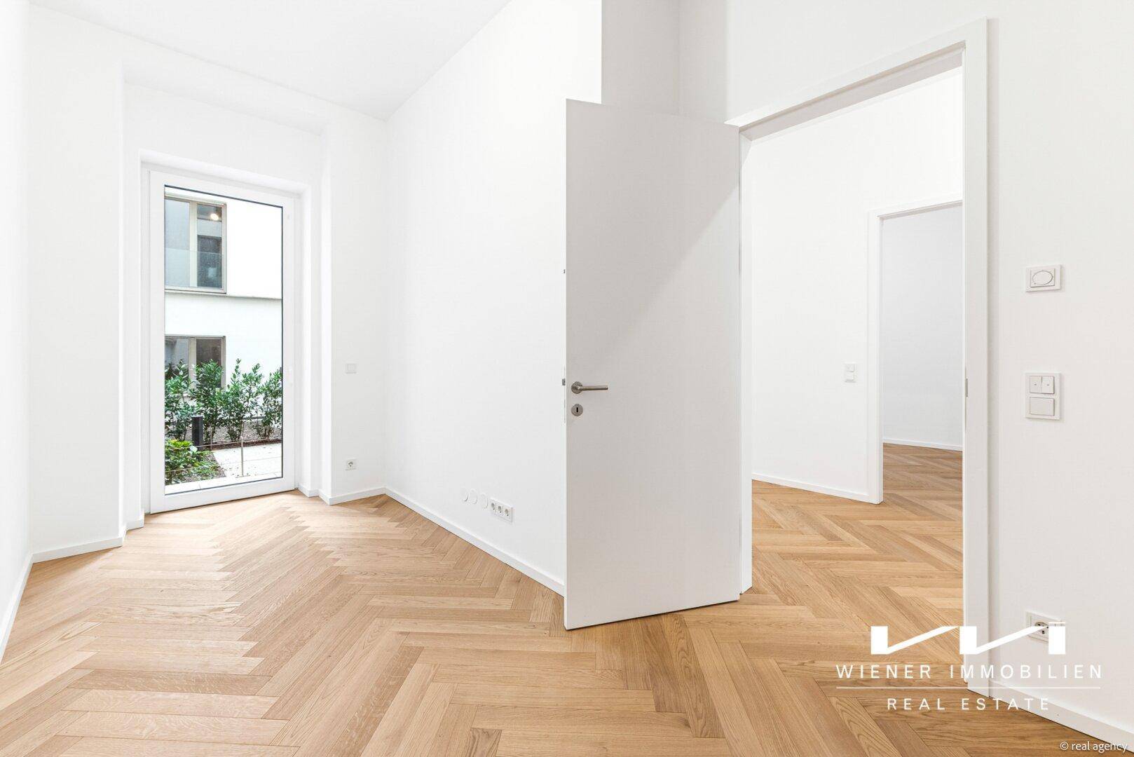 Geräumiges Zimmer mit Fischgrätparkettboden und Blick in den ruhigen Innenhof, ideal für Wohnzwecke.