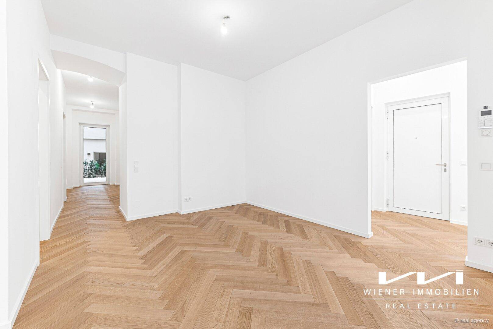 Heller Wohnbereich mit Fischgrätparkettboden und offenem Zugang zum Flur und Eingangsbereich der Wohnung.