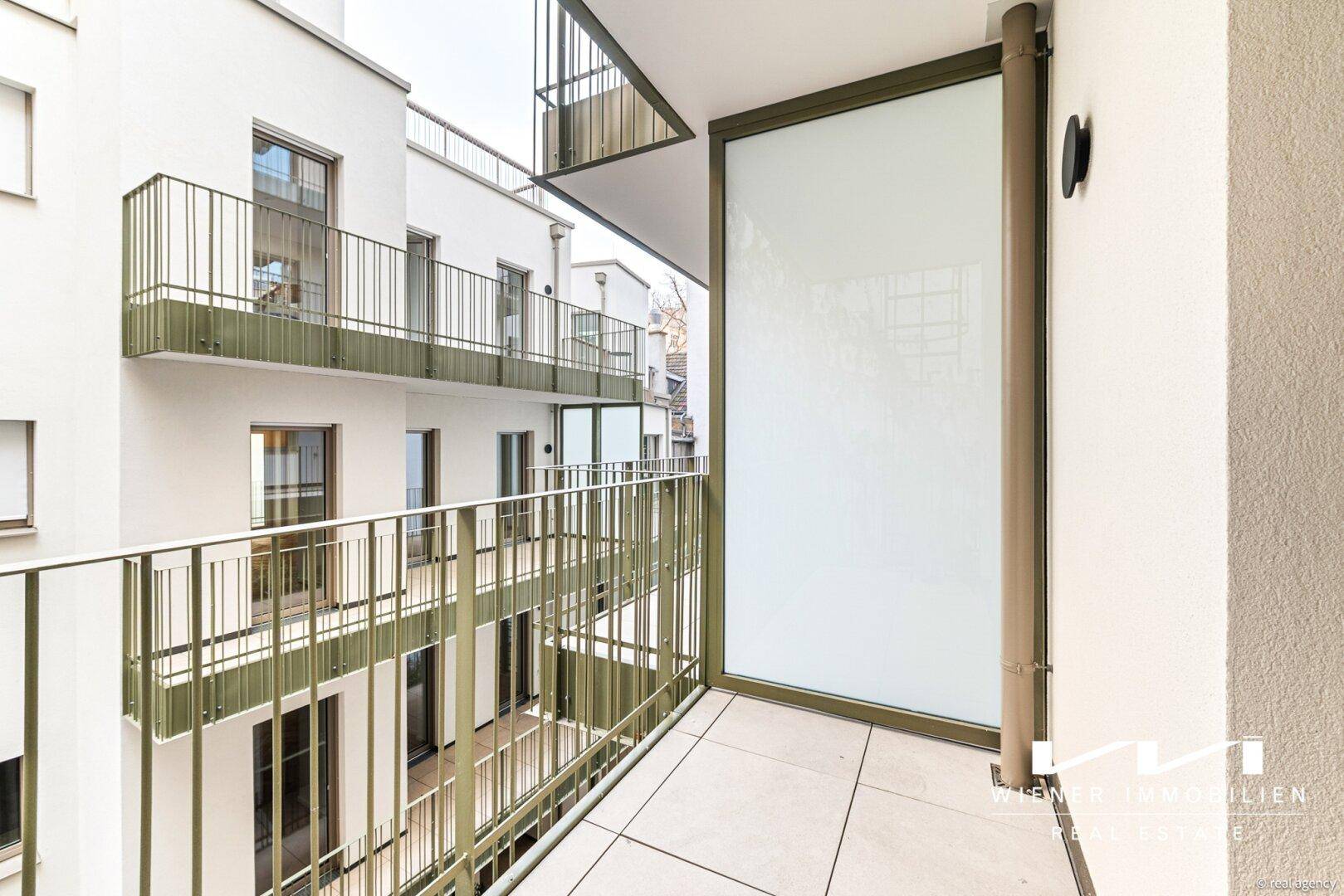 Kleinerer Balkon mit Fliesenboden und Blick auf die umliegenden Gebäudefassaden.