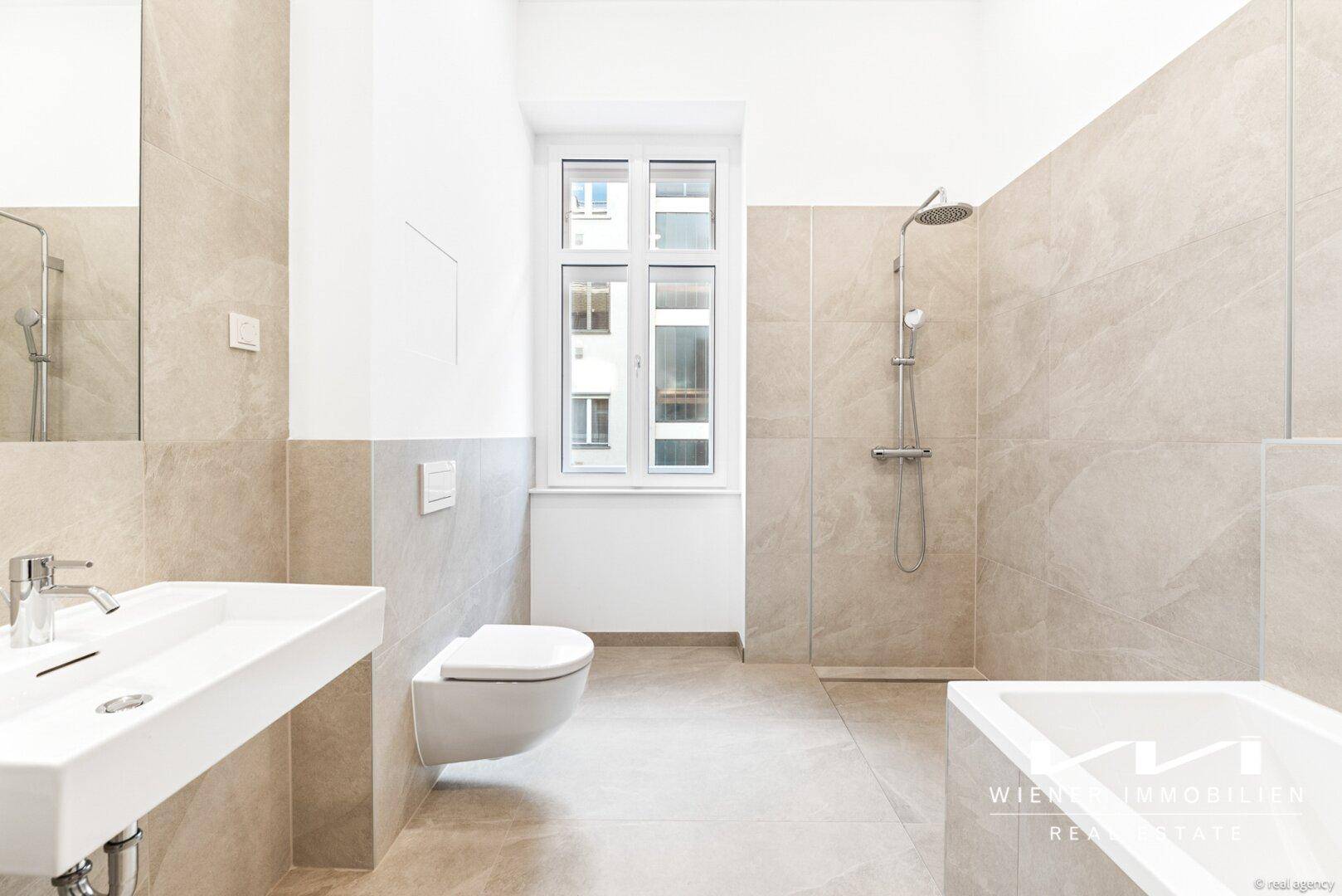 Modernes Badezimmer mit großformatigen Fliesen, Dusche, Badewanne und Fenster für Tageslicht.