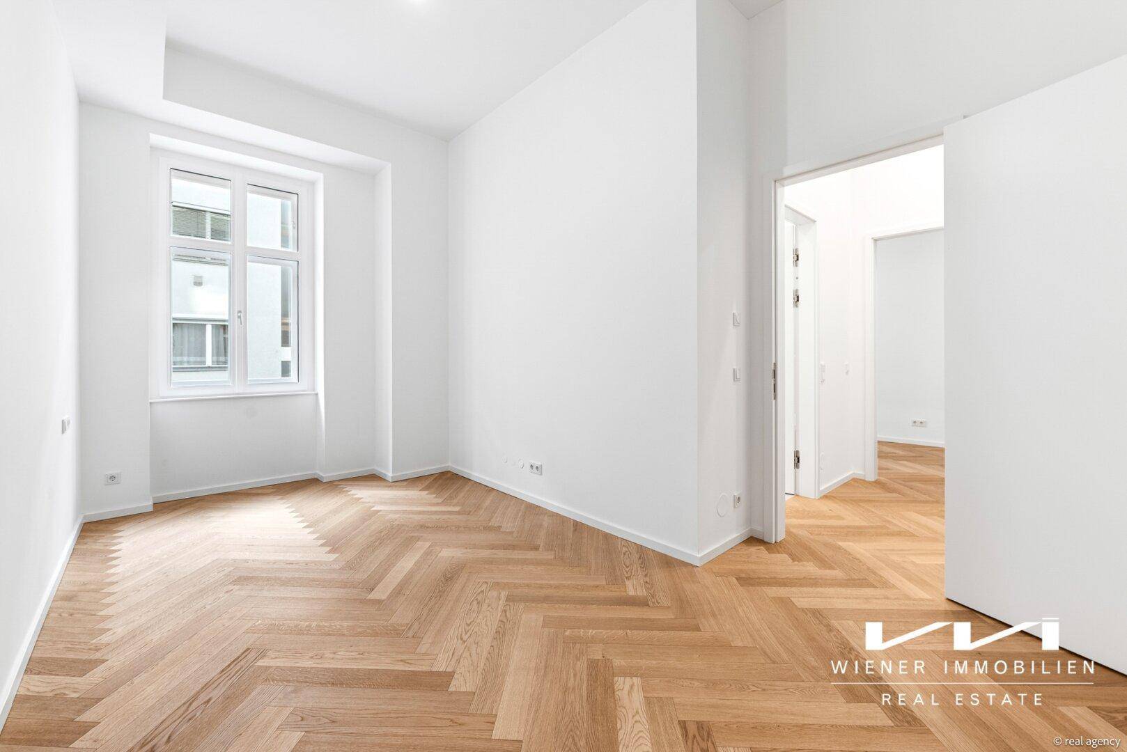 Helles Zimmer mit Fischgrätparkett und großem Fenster, ideal als Schlaf- oder Arbeitszimmer.