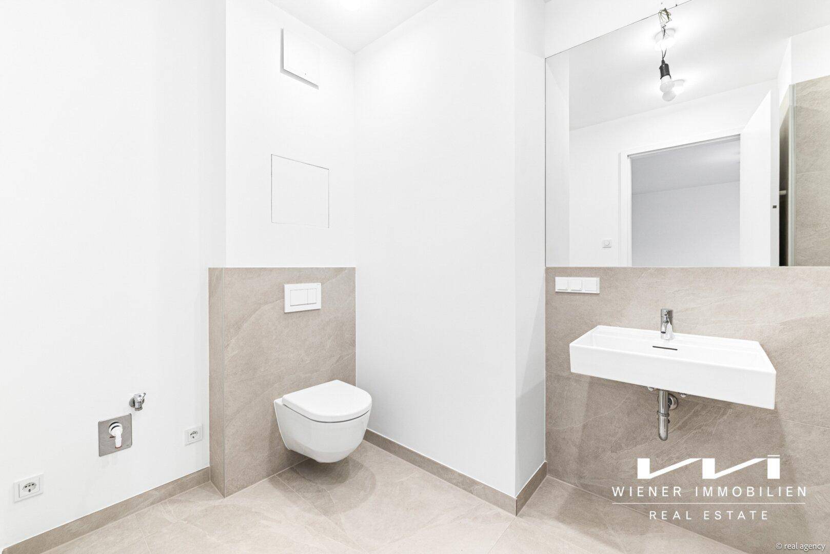 Modernes Gäste-WC mit wandhängender Toilette, Waschbecken und großem Spiegel.