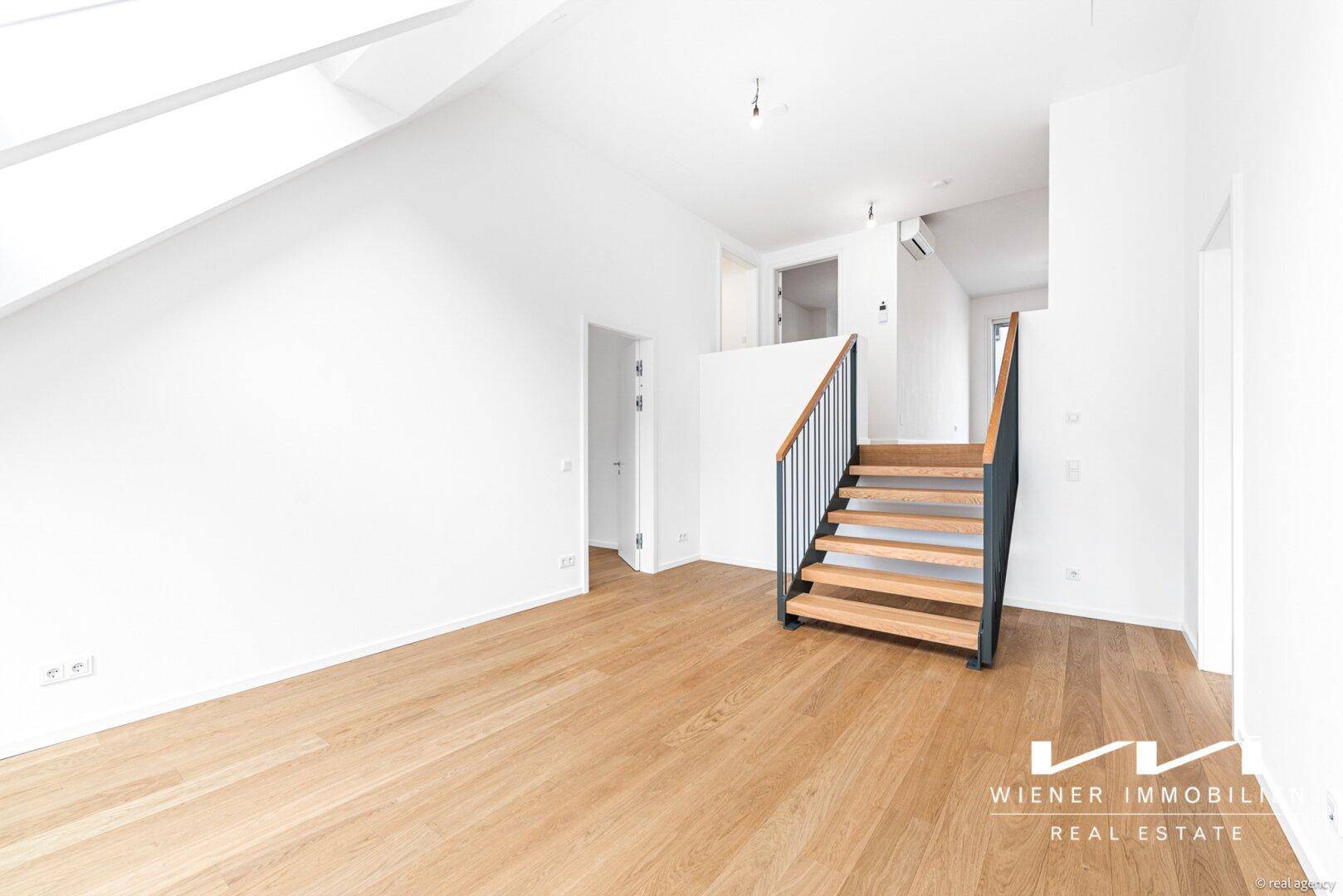 Offener Dachgeschossbereich mit Holzfußboden, moderner Treppe und Klimaanlage.
