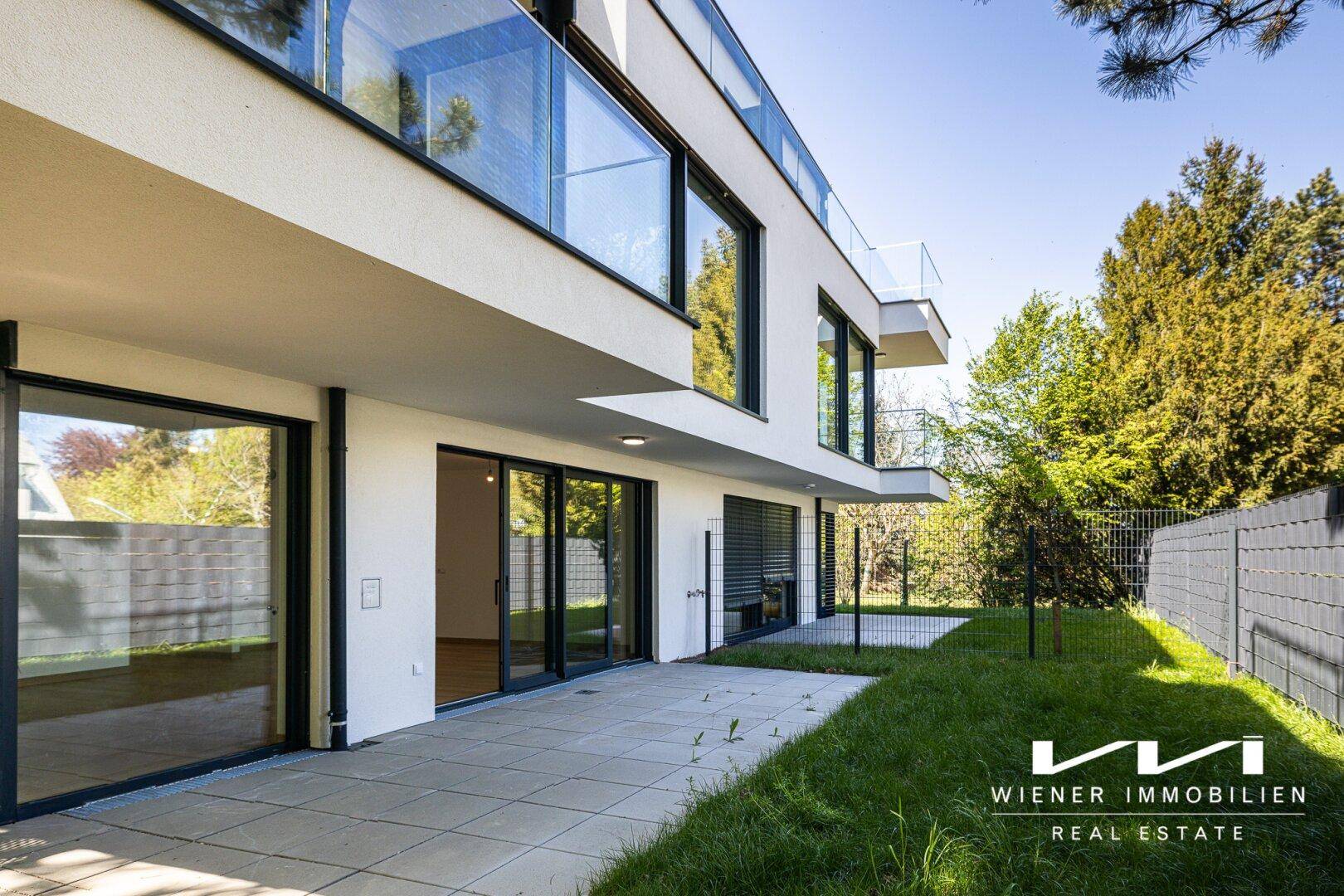 Weitläufige Außenansicht eines modernen Gebäudes mit großer Terrasse und Gartenbereich.