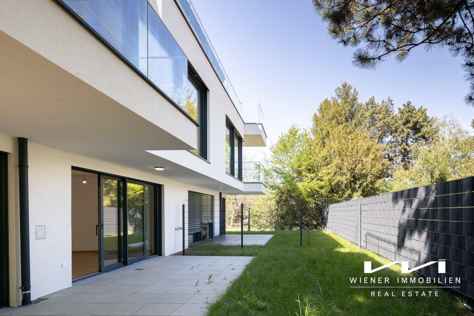 Attraktive moderne Architektur mit weitläufiger Terrasse und Zugang zum grünen Garten.