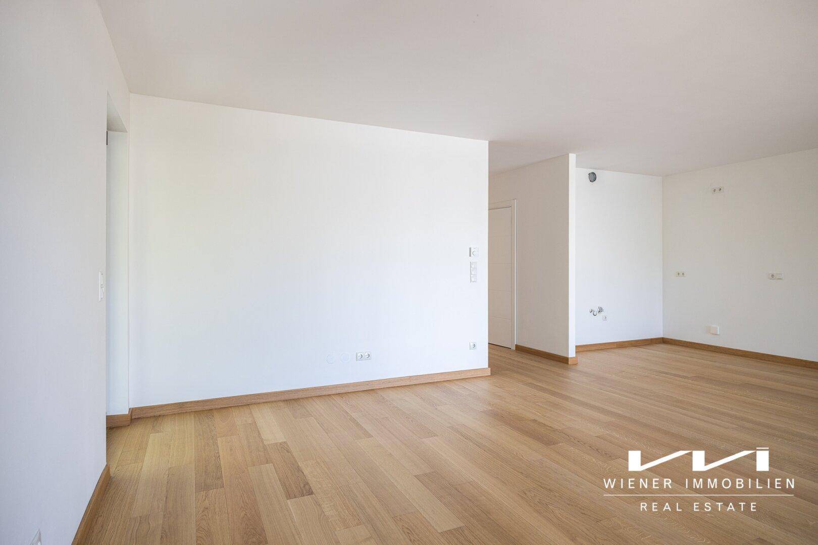 Geräumiger, heller Innenraum mit Holzboden und weißen Wänden, bereit zur individuellen Gestaltung.