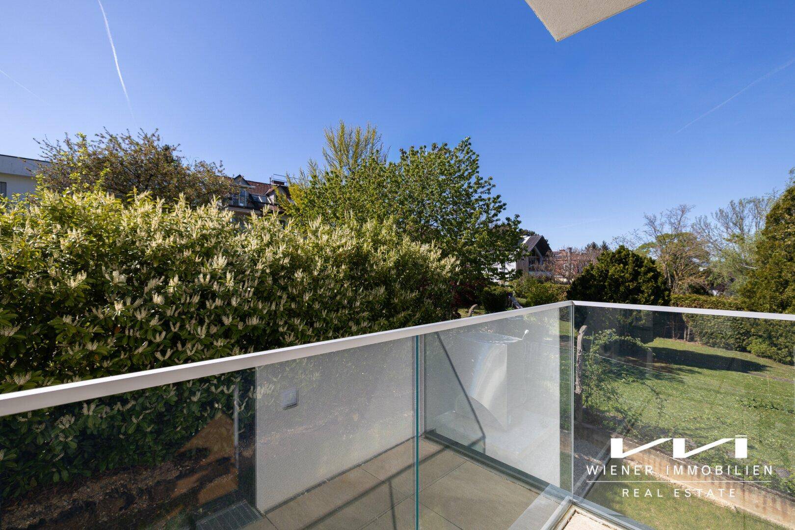 Moderner Balkon mit Glasgeländer und Blick auf die umliegende grüne Landschaft.