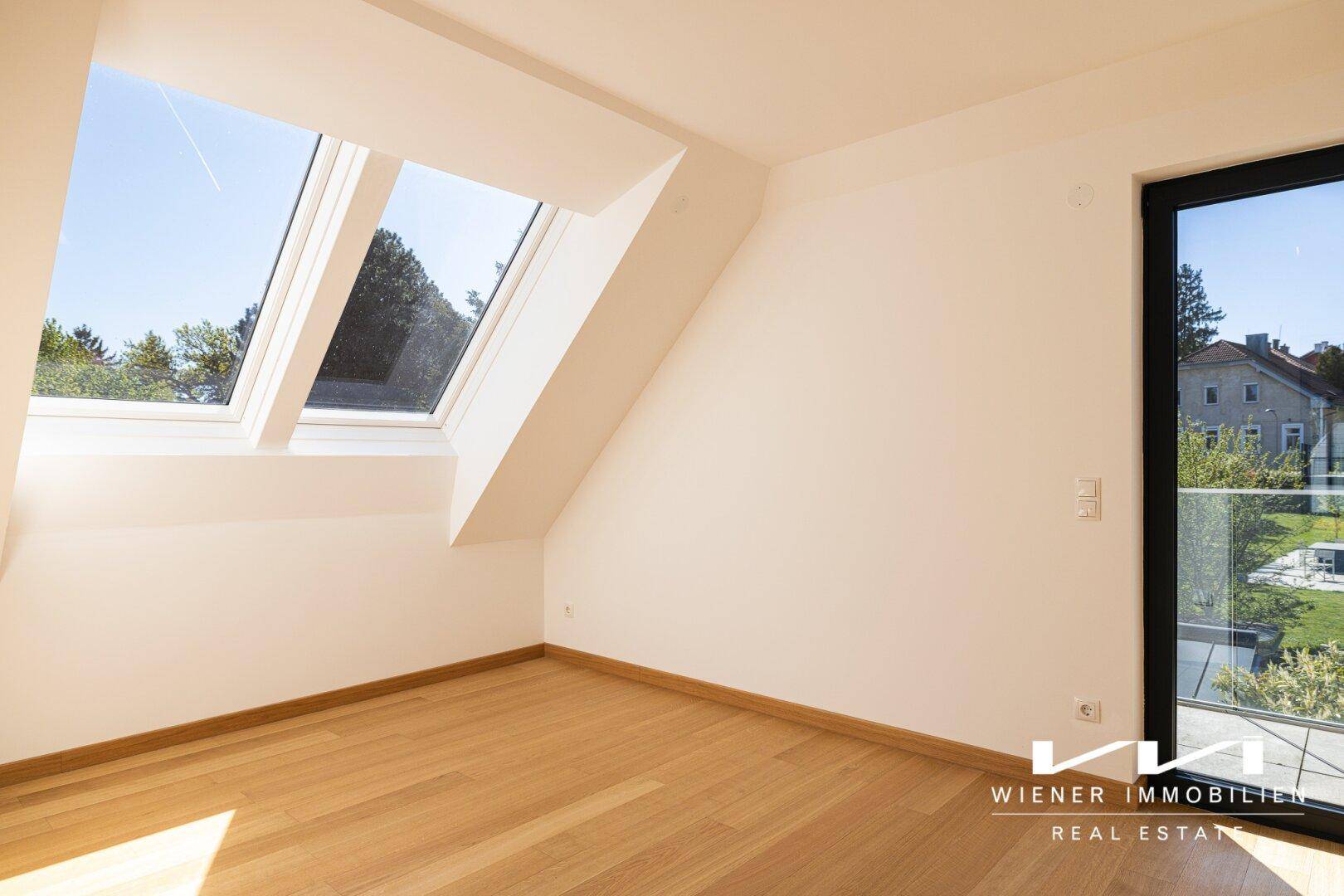 Helles Schlafzimmer mit Holzboden, schräger Decke, Dachfenstern und Zugang zu einem Außenbereich.