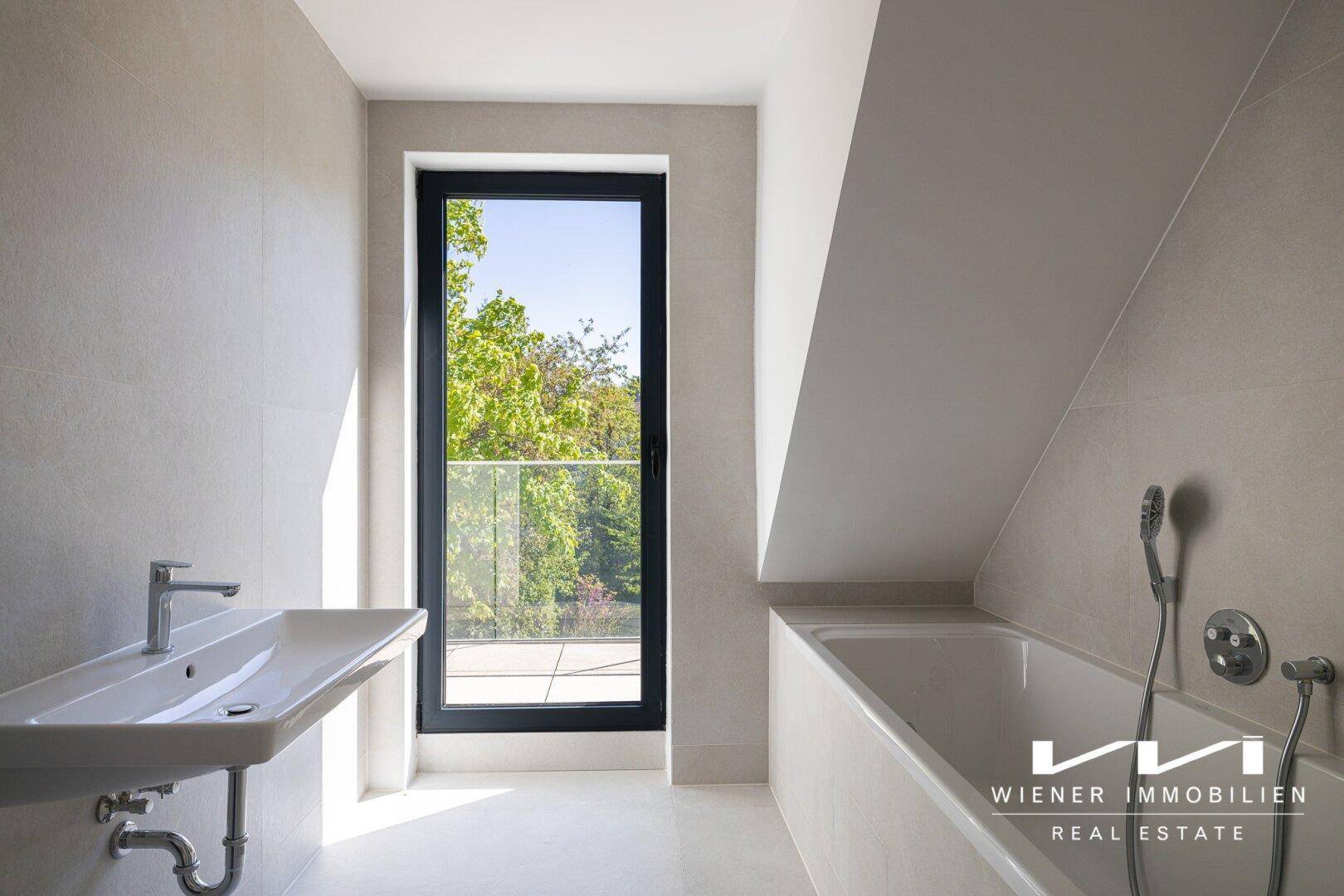 Modernes Badezimmer mit Badewanne, Einzelwaschbecken, Fliesenboden und Zugang zu einem Außenbereich.