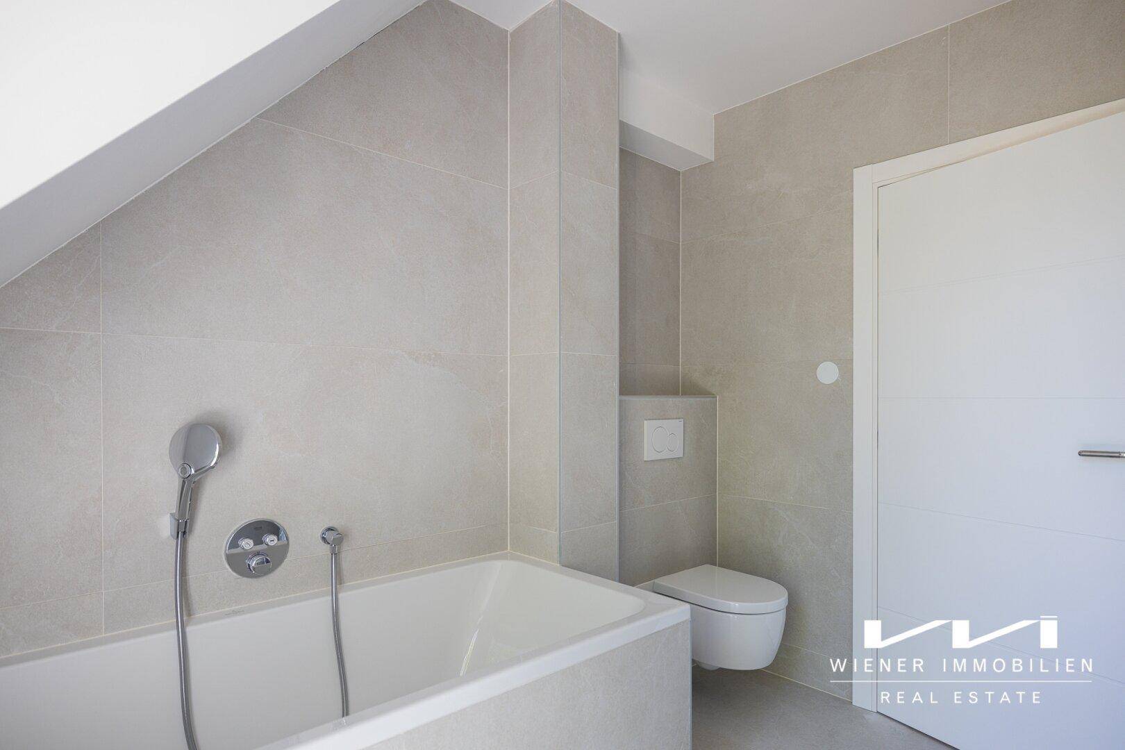 Helles Badezimmer mit Badewanne, wandhängendem WC und modernen Fliesen an Wänden und Boden.