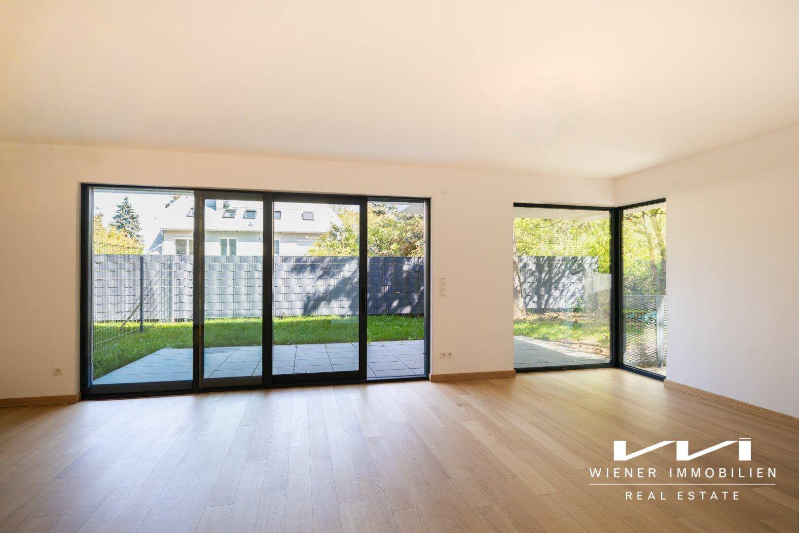 Geräumiges, leeres Wohnzimmer mit großen Fenstern und Zugang zur Terrasse und zum Garten.