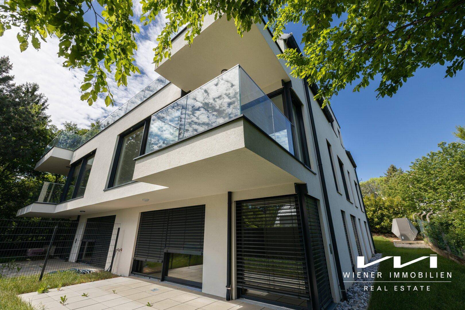 Modernes Mehrfamilienhaus mit Balkonen, großen Fenstern und Zugang zum Gartenbereich.