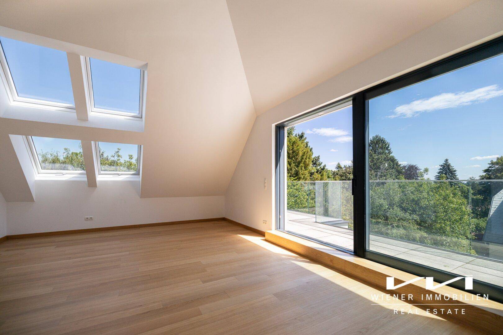 Lichtdurchfluteter Wohnbereich im Dachgeschoss mit großen Fenstern und Holzboden.