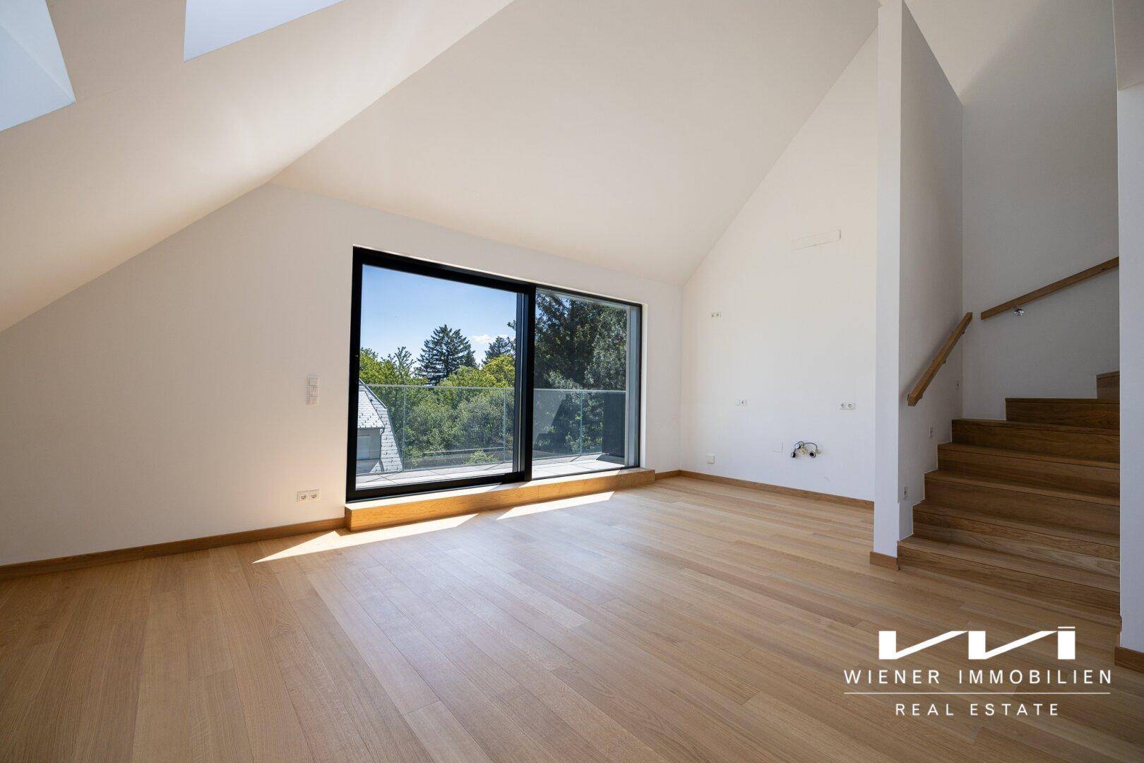 Geräumiger Wohnbereich mit Holzboden, großen Fenstern und offener Treppe.