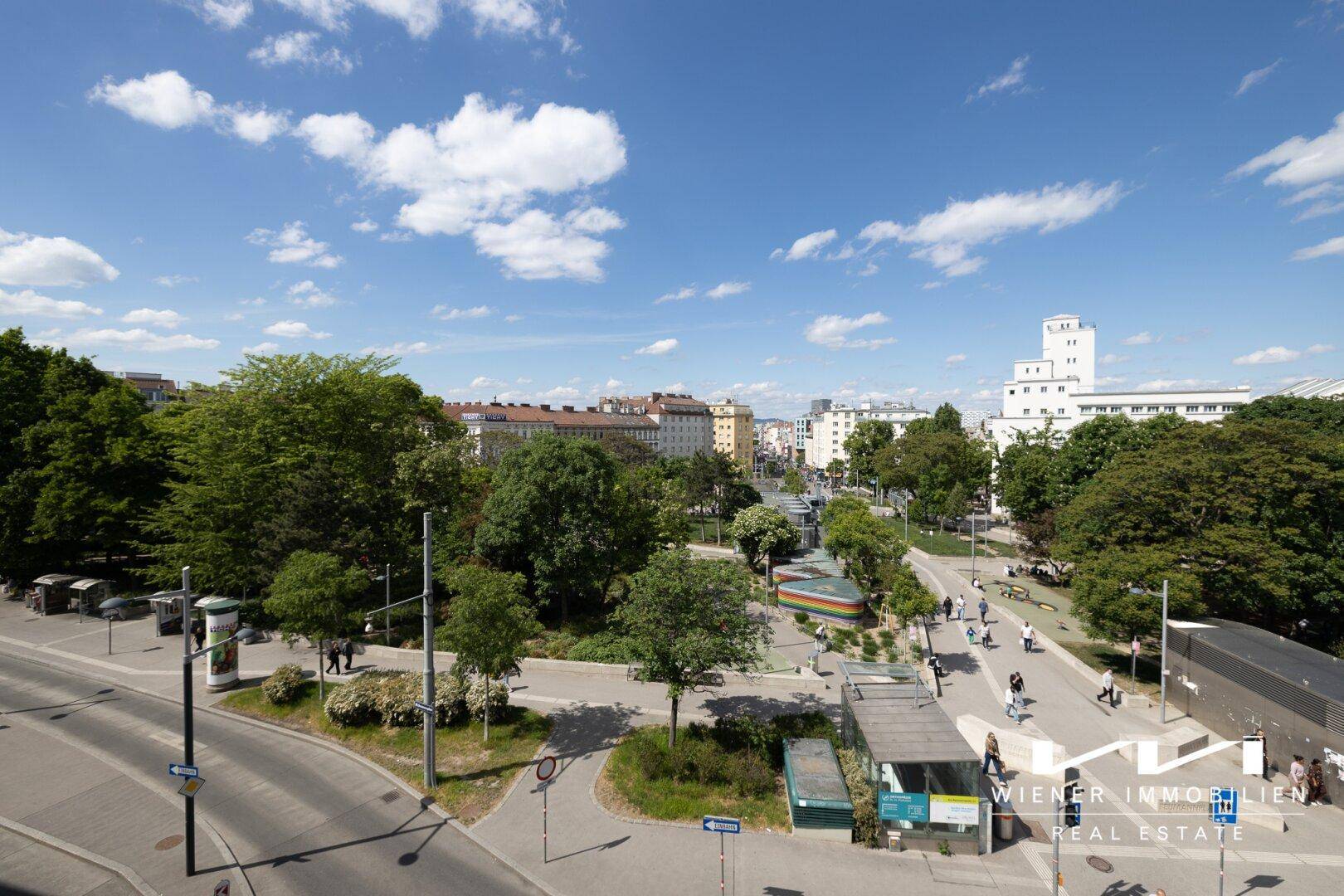 Panoramablick auf eine städtische Umgebung mit Parkanlagen und blauen Himmel.