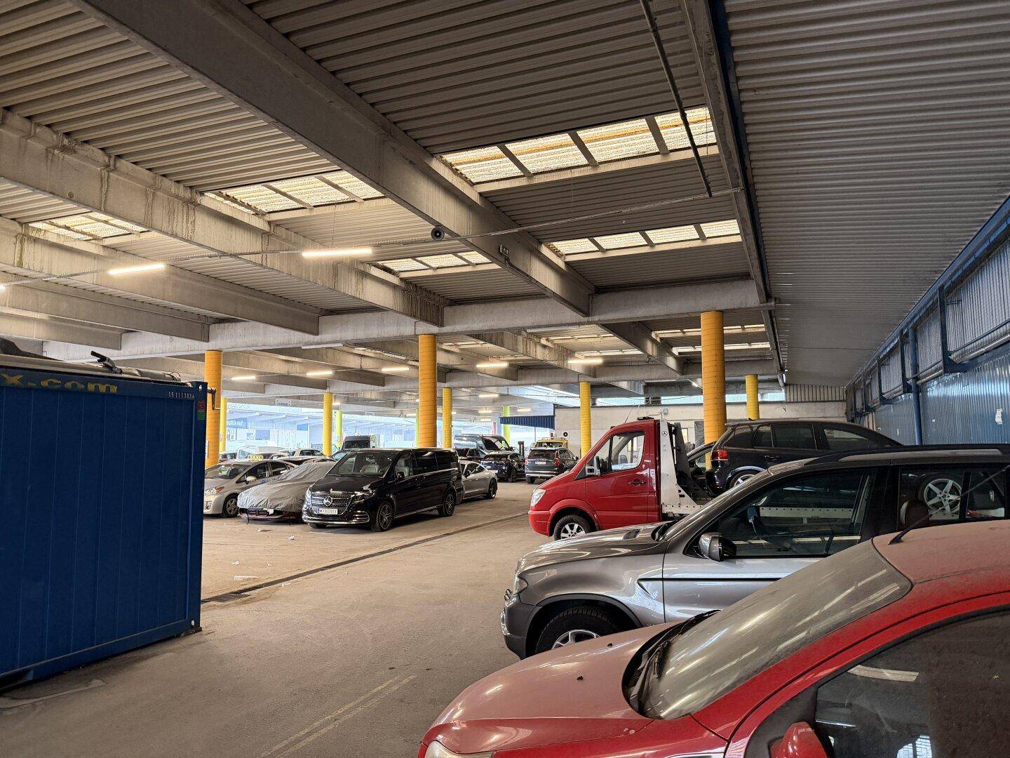 Überdachte Parkgarage mit vielen Fahrzeugen und Oberlichtern, die natürliches Licht hereinlassen.