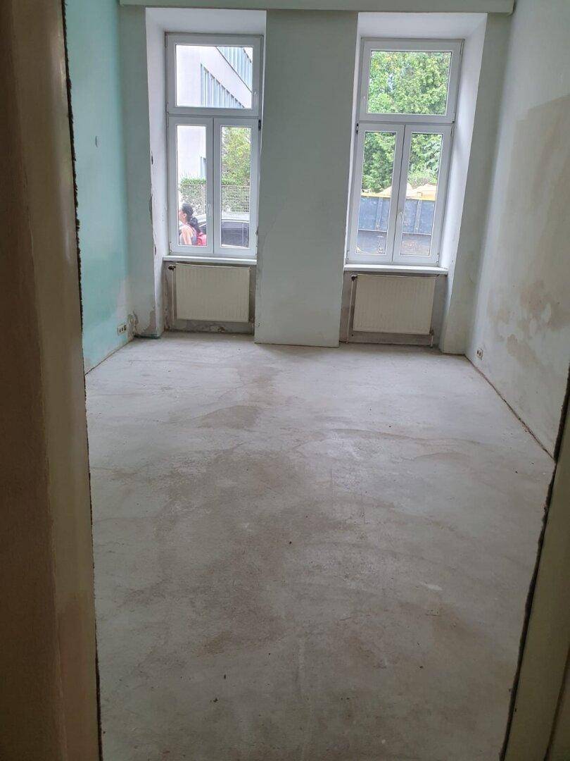 Heller Raum in Renovierung mit zwei Fenstern und Heizkörpern, bereit für die Gestaltung.