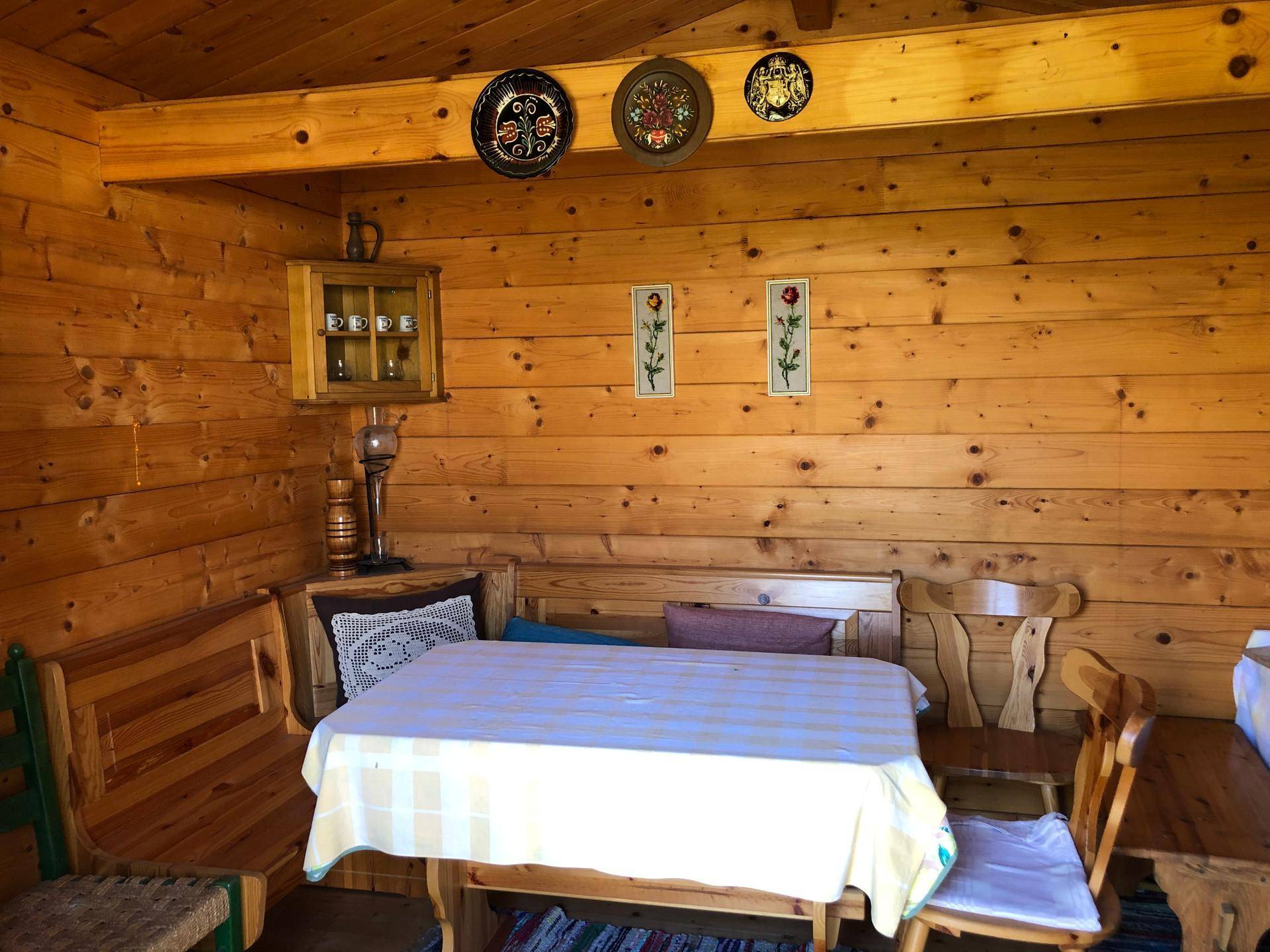 Gemütlicher Innenraum des Holzschuppens mit Holztäfelung, Esstisch und traditioneller Dekoration.