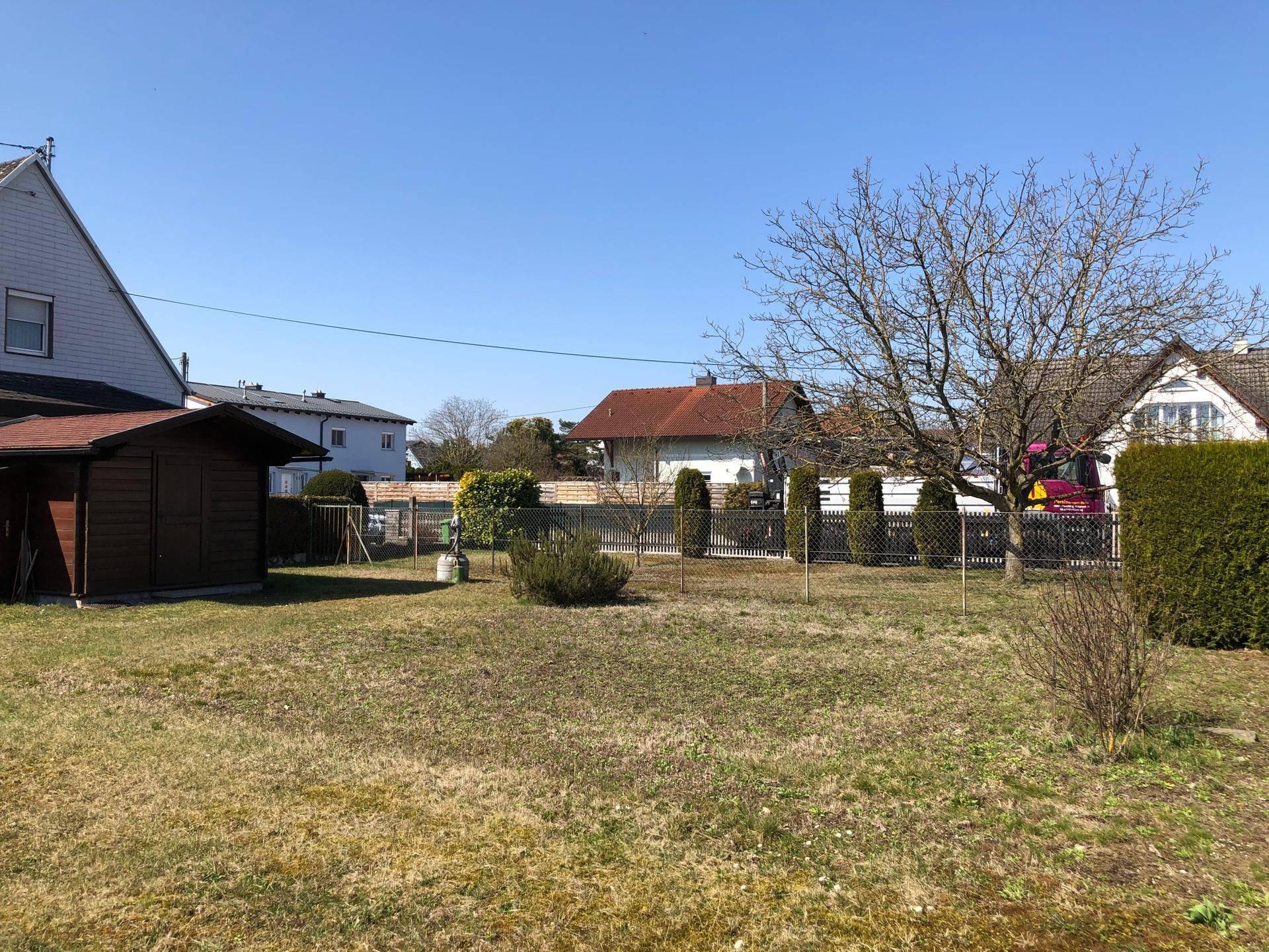 Weitläufiger Gartenbereich mit Rasenfläche, Bäumen und Blick auf die Nachbarschaft.