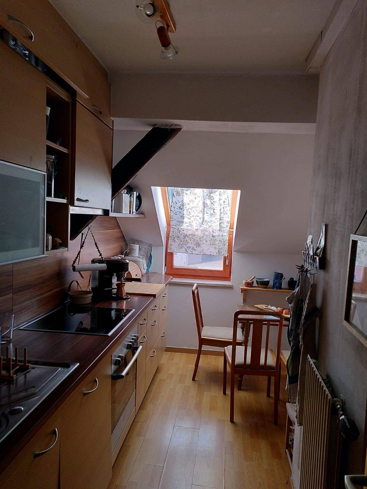 Schmale Küche im Dachgeschoss mit Holzfronten, Einbaugeräten und einem praktischen Dachfenster.