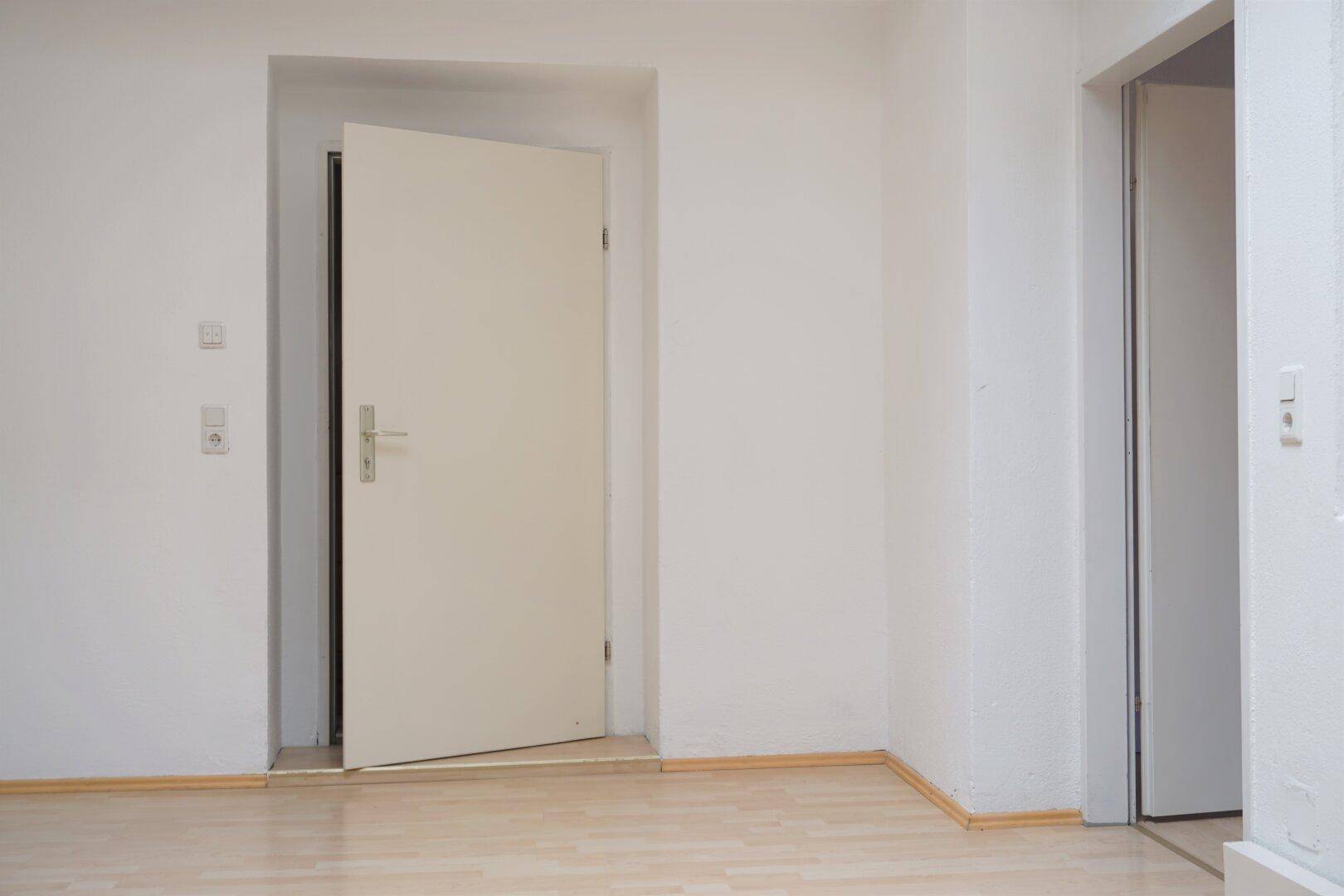 Heller Flur mit Holzboden und zwei Türen, die zu weiteren Räumen führen, in einem gepflegten Zustand.