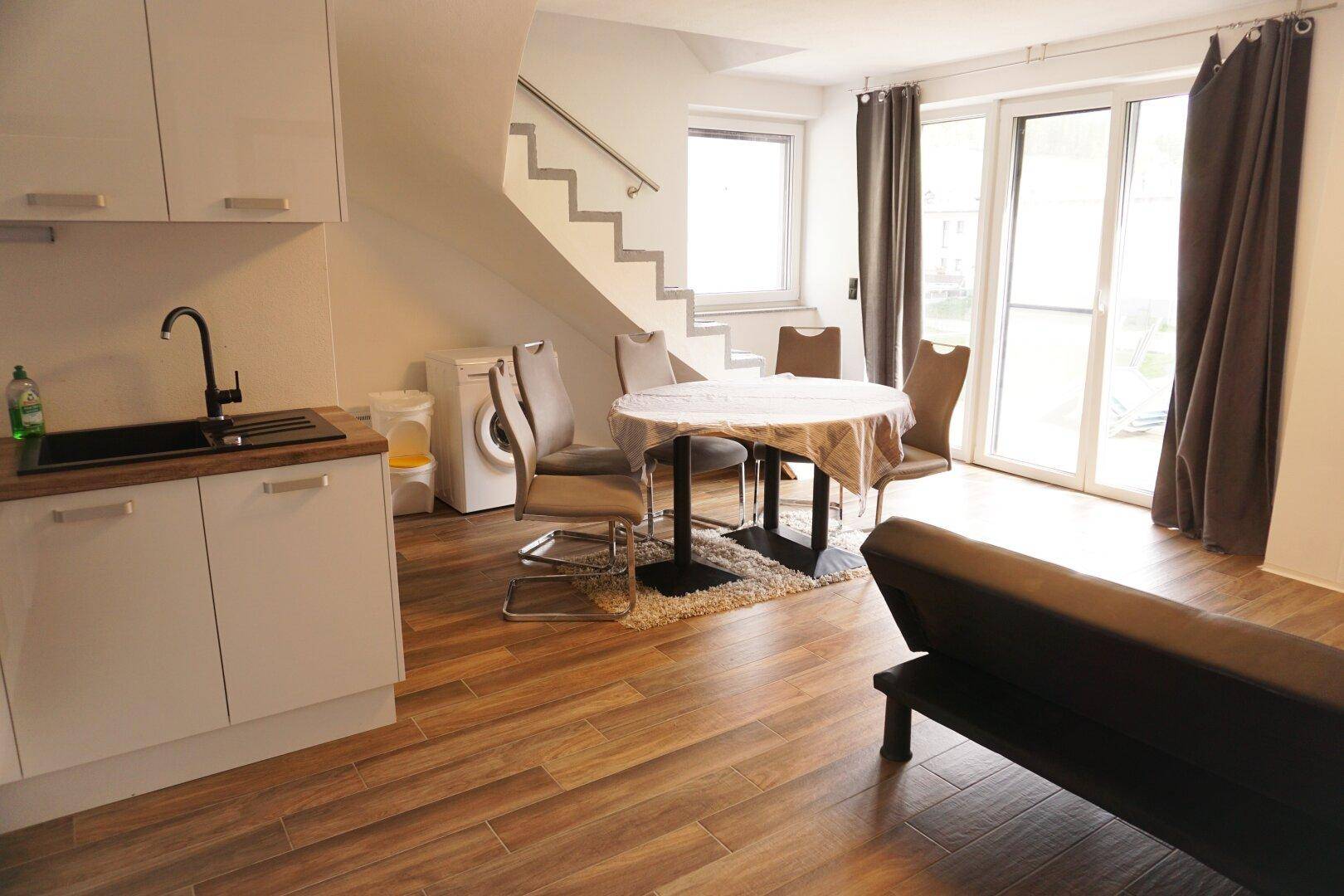 Offener Wohnbereich mit Küchenzeile, Esstisch und Zugang zur Terrasse, ideal für kleine Familien.