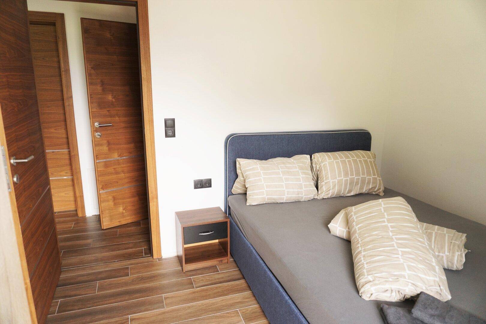 Kleines Schlafzimmer mit Einzelbett, Holzboden und Holztüren, ideal als Gästezimmer.