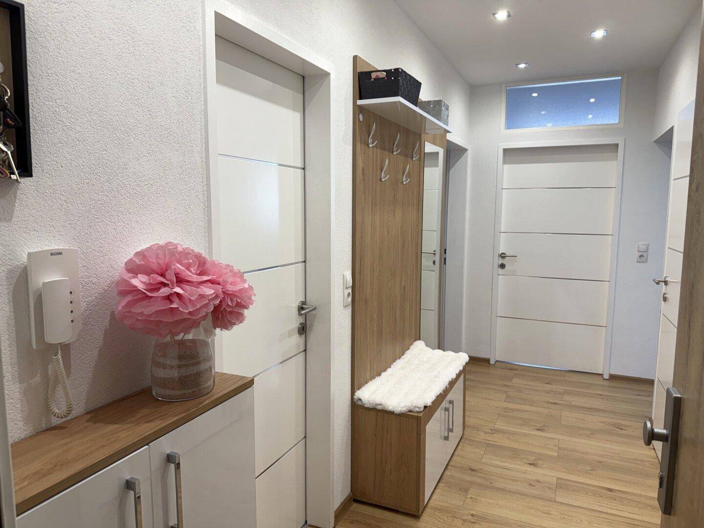 Heller Flur mit Garderobe, Holzboden und modernen Türen, einladend gestaltet.