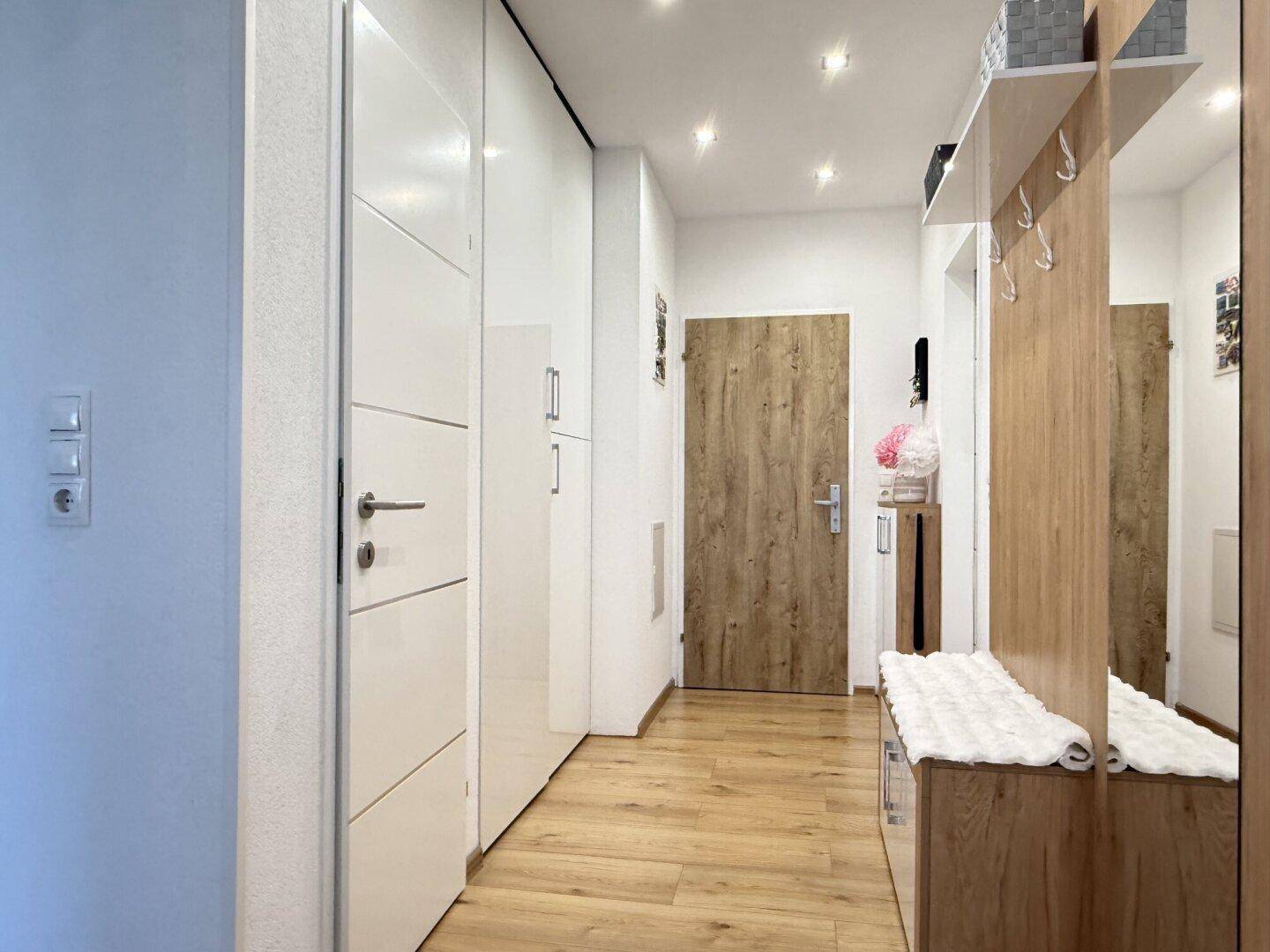 Geräumiger Flur mit Einbauschränken, Garderobe und hellem Holzboden.