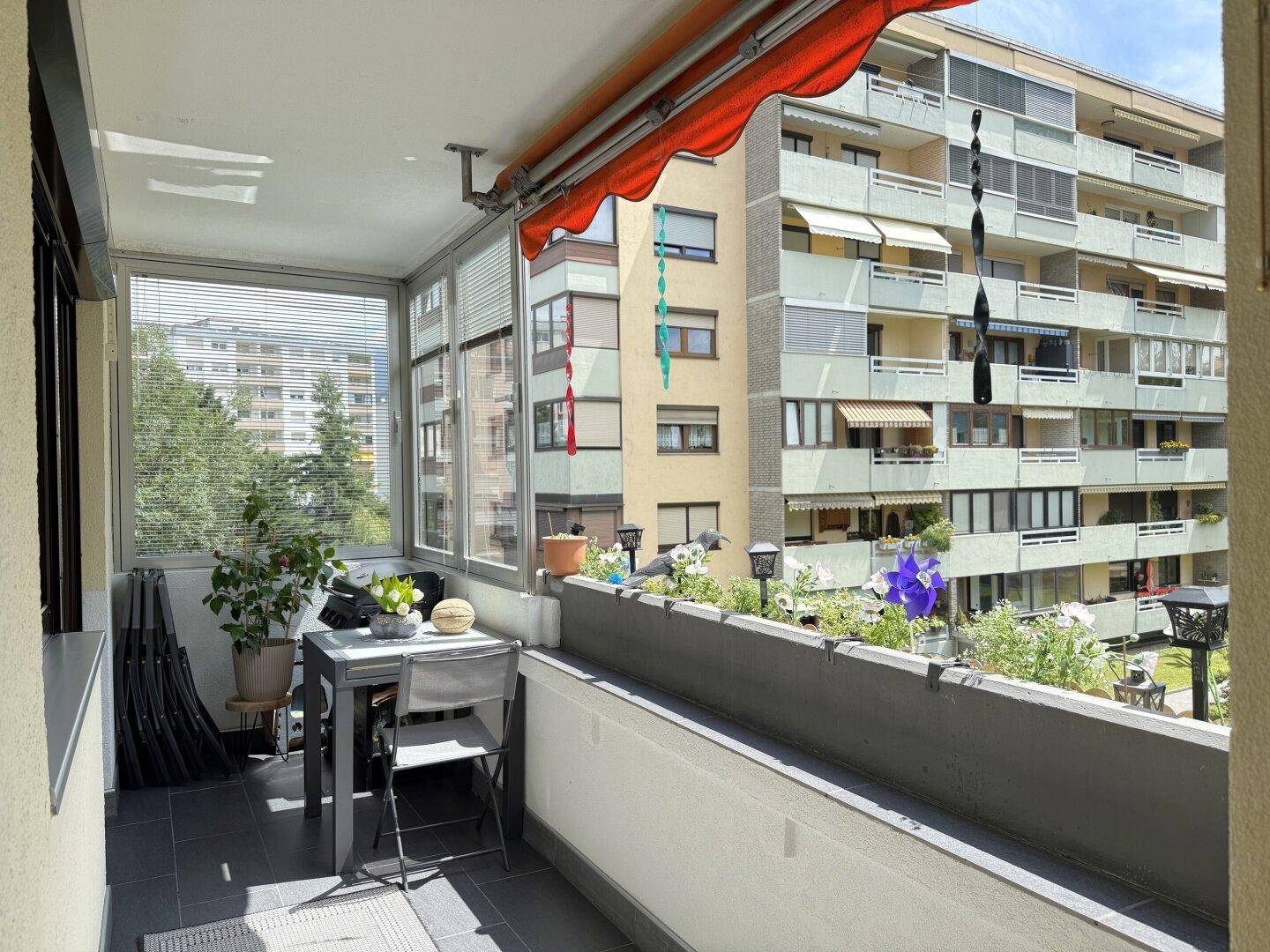 Geräumiger Balkon mit Markise, Blumenkästen und weitem Blick auf die Umgebung.