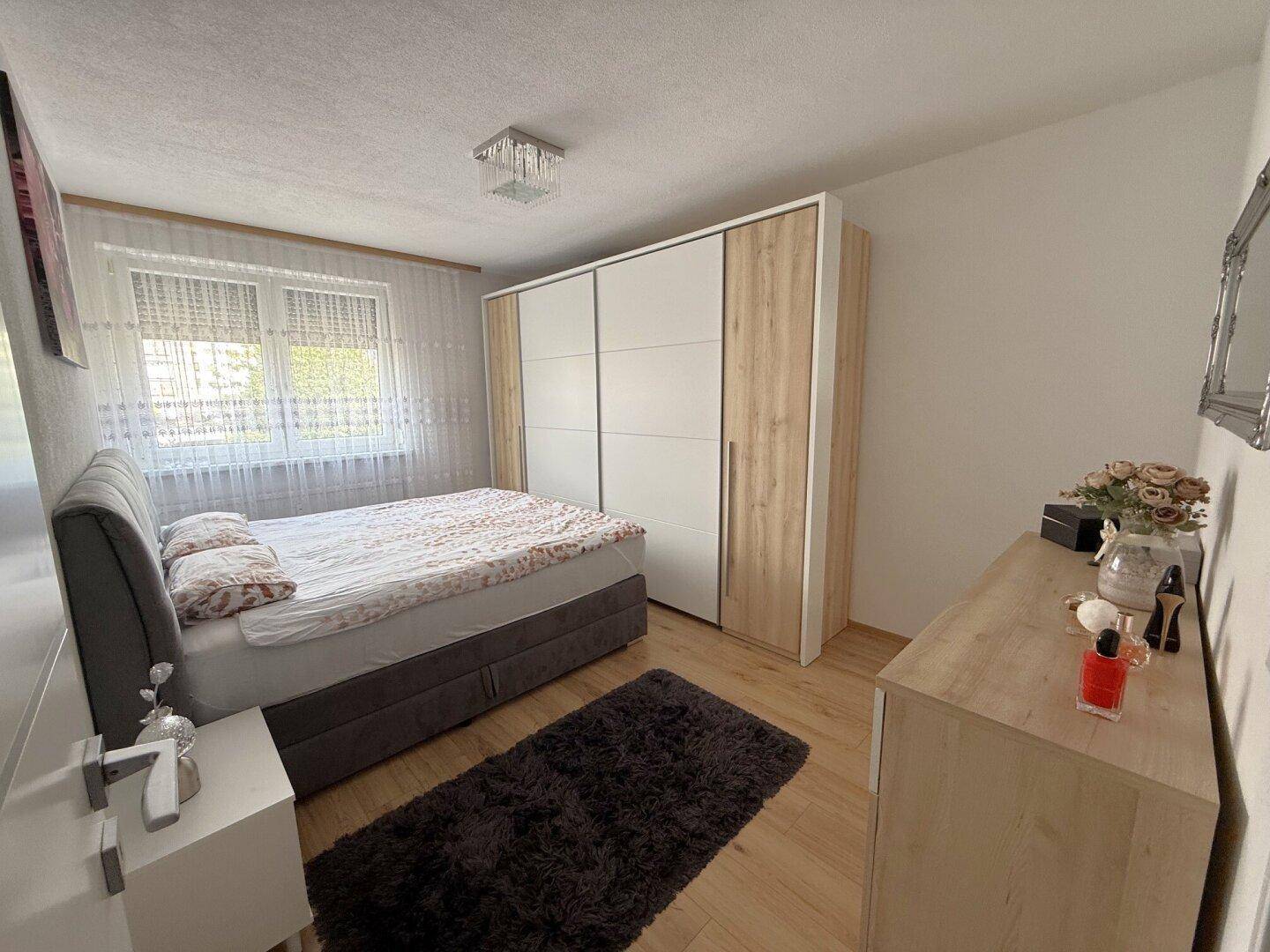 Helles Schlafzimmer mit großem Kleiderschrank, Doppelbett und Holzboden.