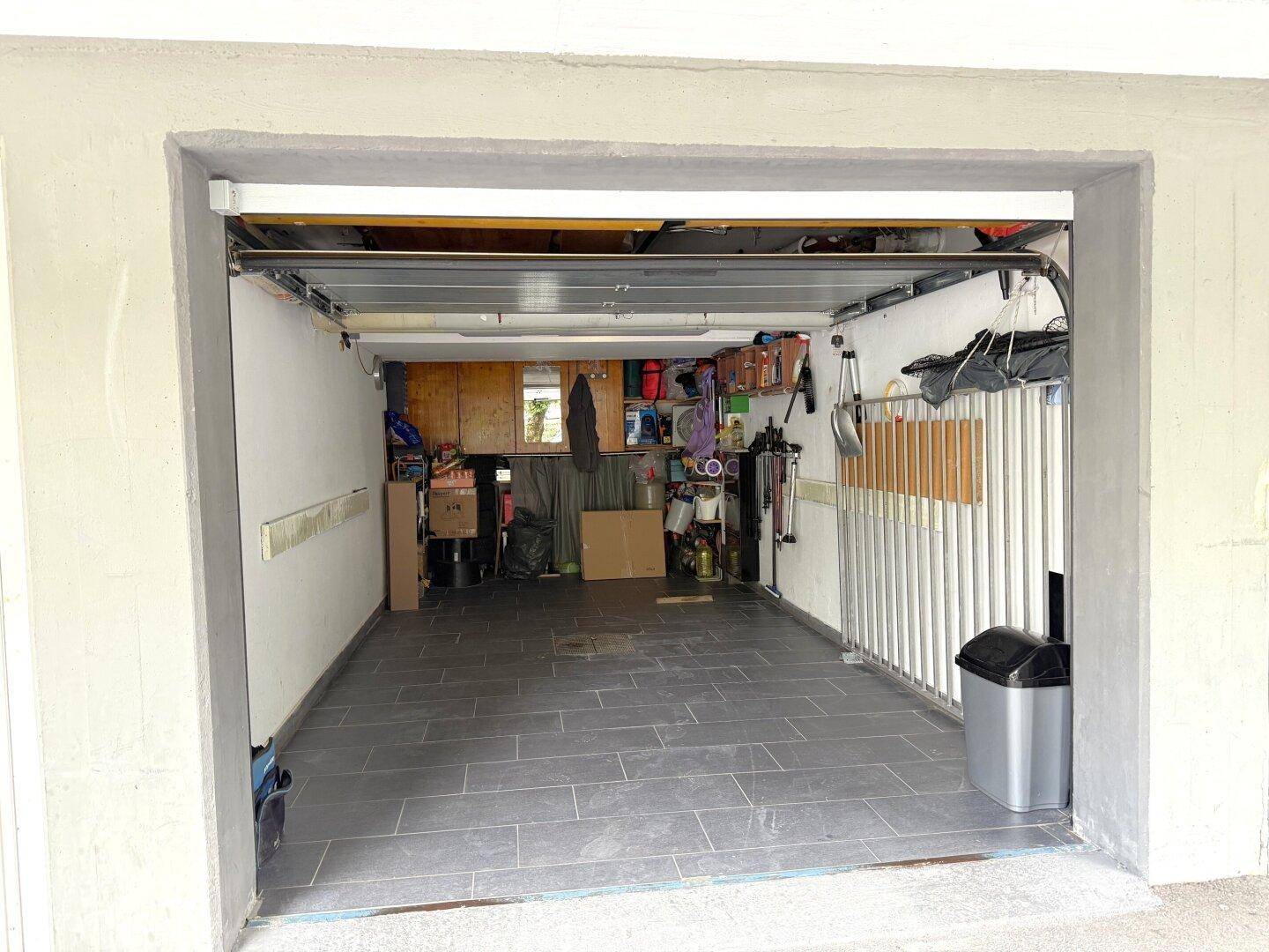 Geräumige Einzelgarage mit Fliesenboden und ausreichend Platz für ein Fahrzeug und Lagerung.