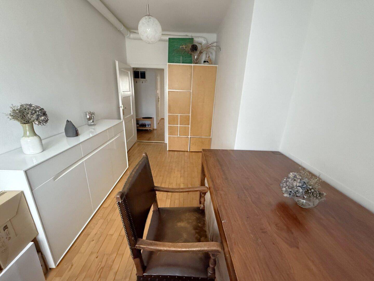 Geräumiges Zimmer mit Holztisch, Sideboard und Zugang zum Flur, vielseitig nutzbar.