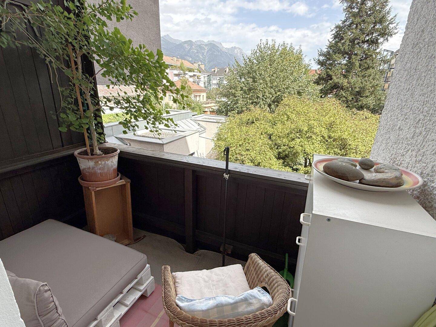Gemütlicher Balkon mit Sitzgelegenheiten, Pflanzen und Blick auf die Berge und Umgebung.