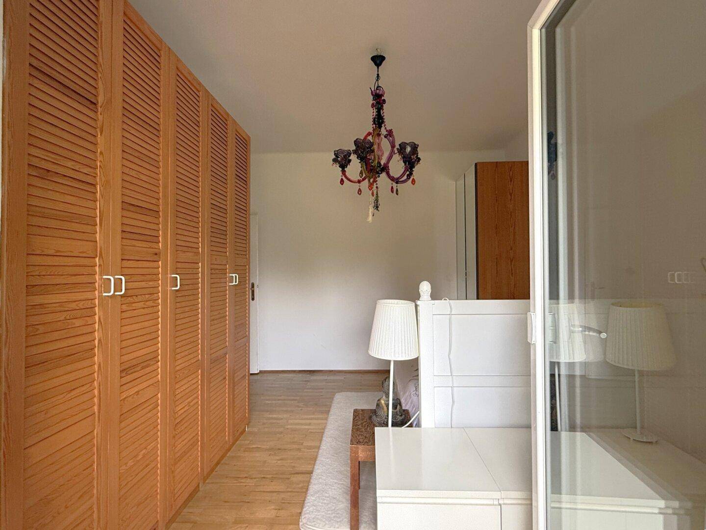 Schlafzimmer mit großem Holzschrank und hellem Ambiente, in gepflegtem Zustand.