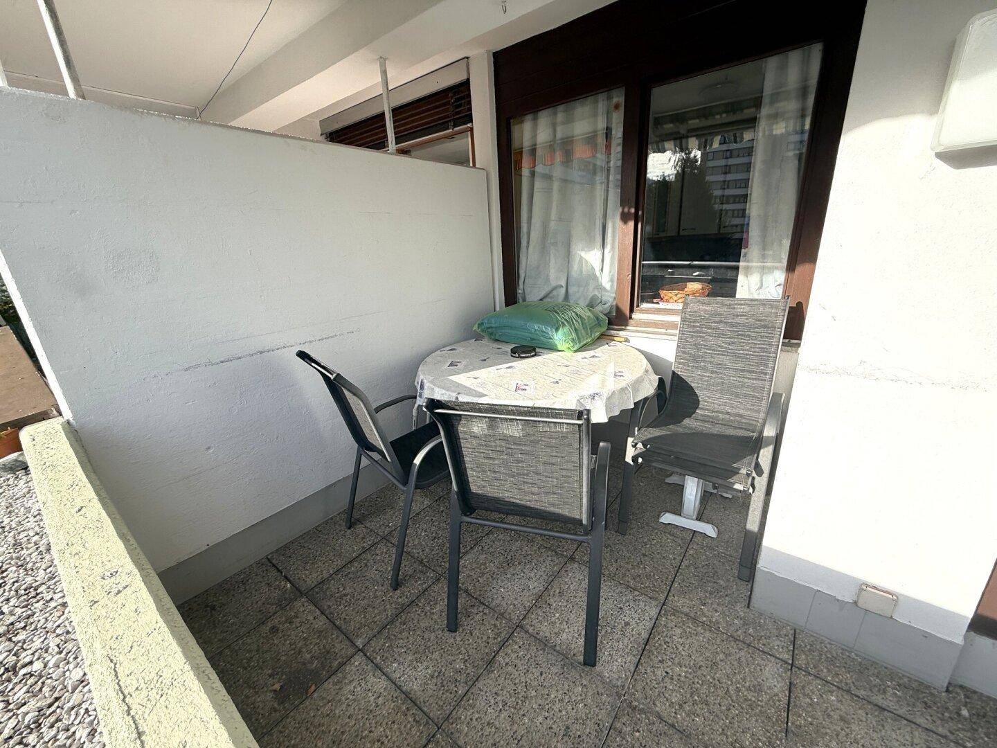 Gemütlicher Sitzbereich auf dem Balkon mit Tisch und Stühlen auf Fliesenboden.
