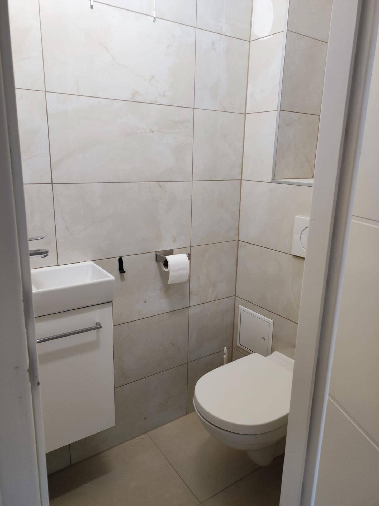 Kleines Gäste-WC mit wandhängender Toilette und einem kompakten Waschbecken.