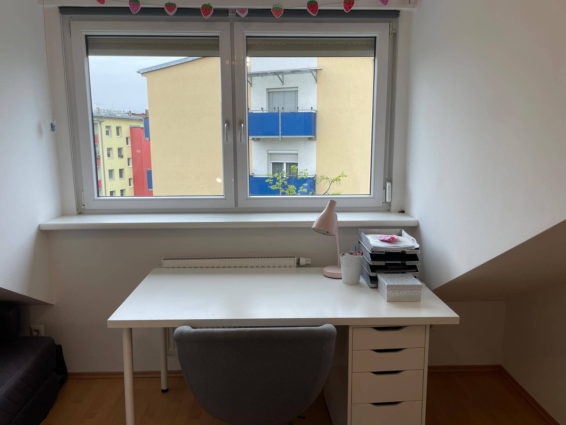 Fenster im Schlafzimmer mit Blick auf die umliegenden Gebäude und Balkone.
