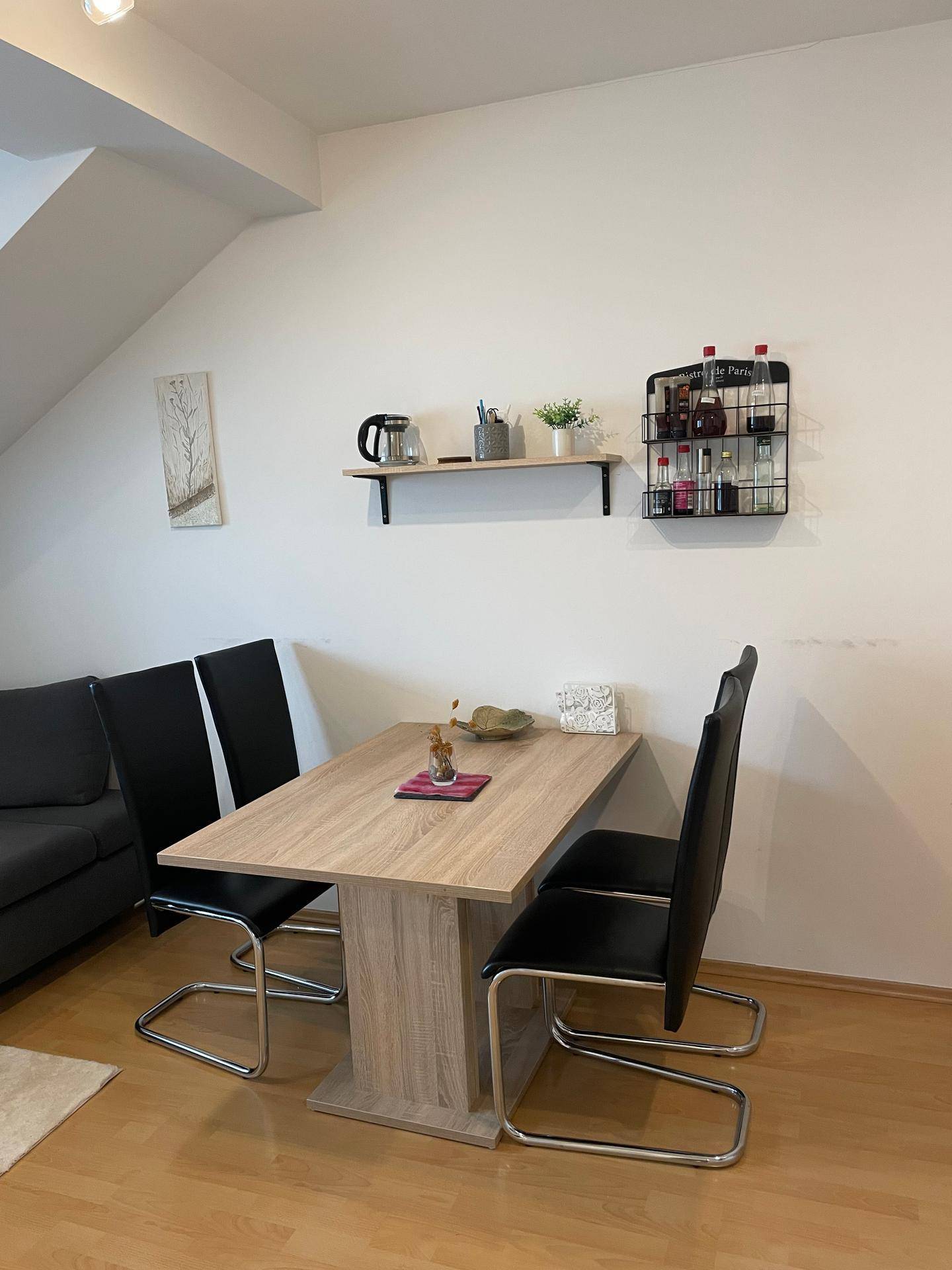 Gemütlicher Essbereich mit Holztisch und schwarzen Stühlen in einem Dachgeschossraum.