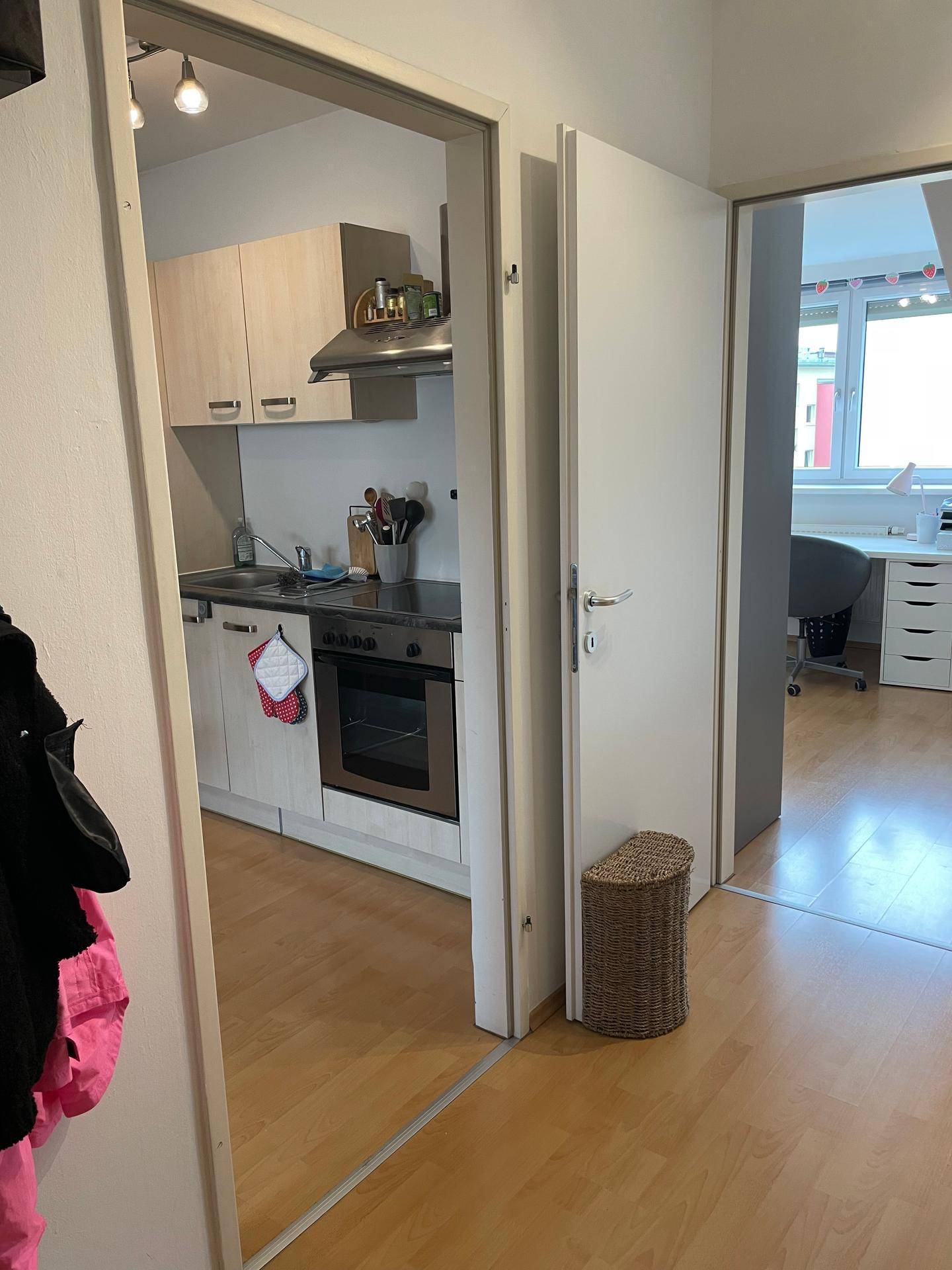 Durchgangsbereich mit Blick in die Küche und einen weiteren Raum mit Fenster.