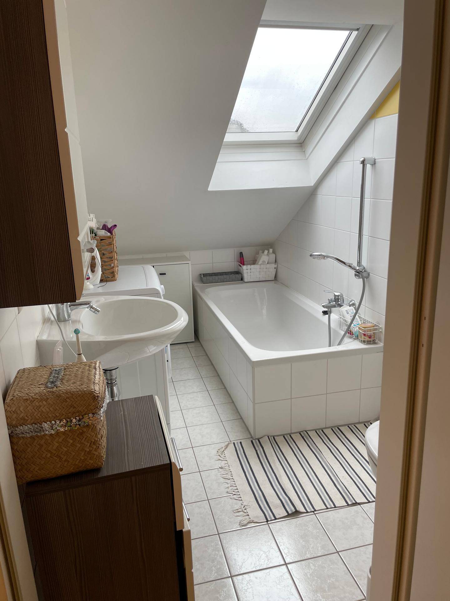 Badezimmer mit Badewanne, Dachschräge und Oberlicht, das viel Tageslicht spendet.