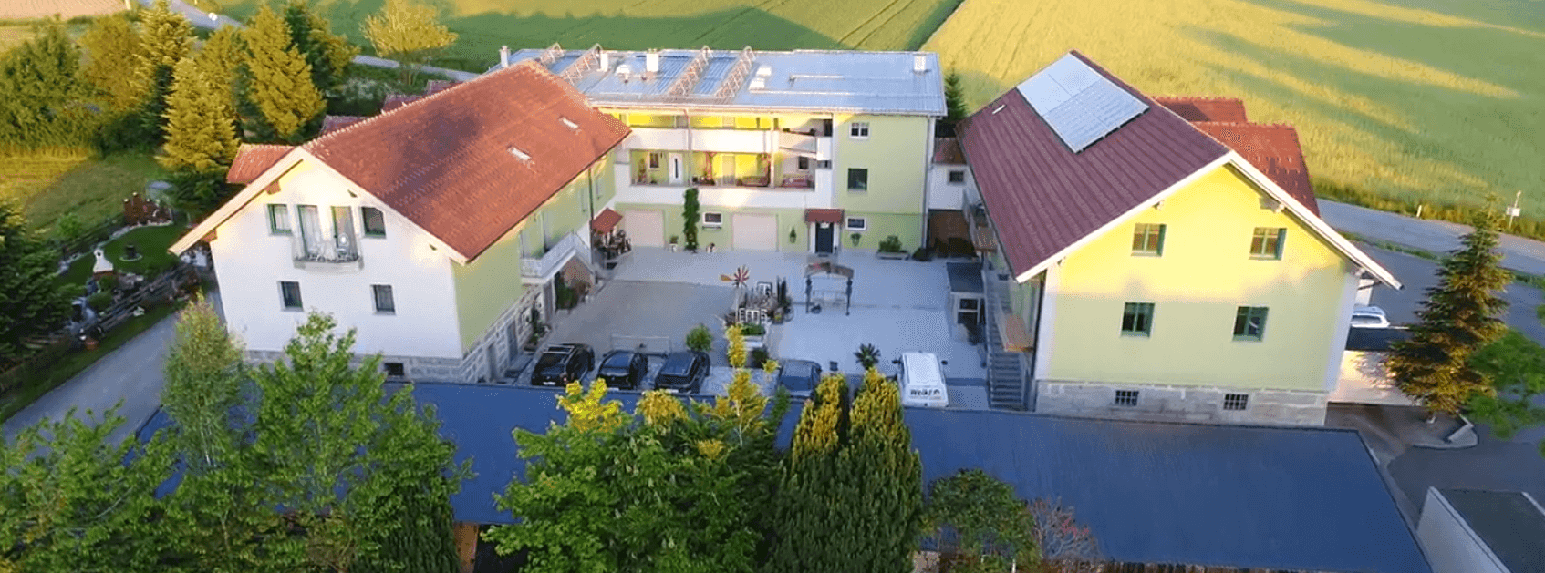 Weitläufiges Anwesen mit mehreren Gebäuden, Innenhof und umliegenden Feldern aus der Vogelperspektive.