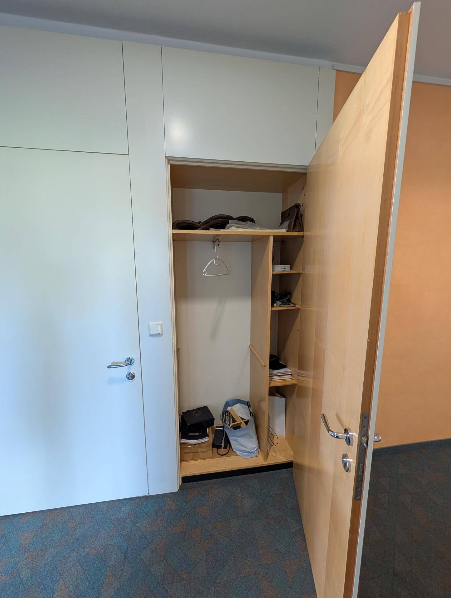 Eingebauter Schrank mit offenen Fächern und Kleiderstange, ideal für Kleidung oder Lagerung von Gegenständen.