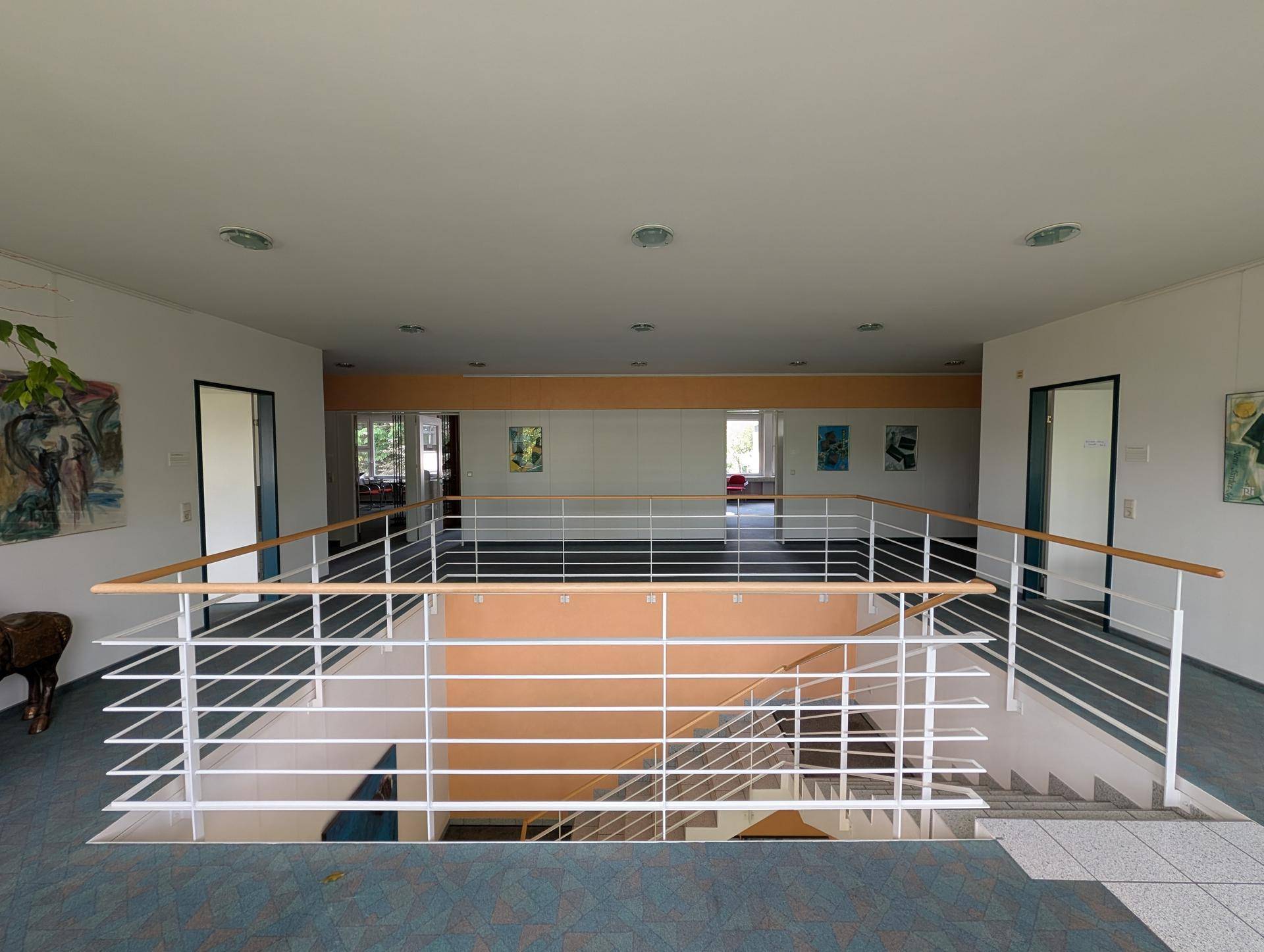 Heller Flur im Obergeschoss mit Blick auf das Treppenhaus und mehrere Bürotüren, modern gestaltet.