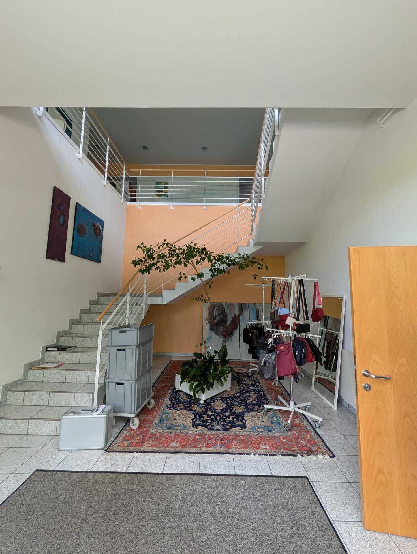 Geräumige Eingangshalle mit Treppenhaus, Galerie und einem großen Teppich als Blickfang im Zentrum.