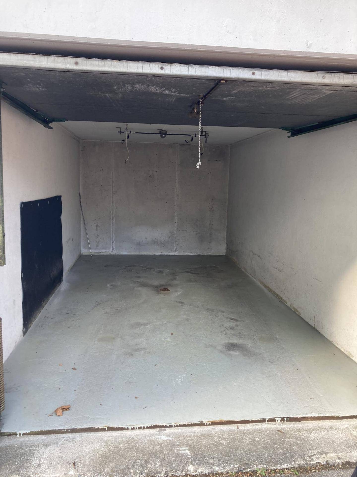 Leere Garage mit Betonboden und aufgerolltem Garagentor, bereit zur Nutzung.