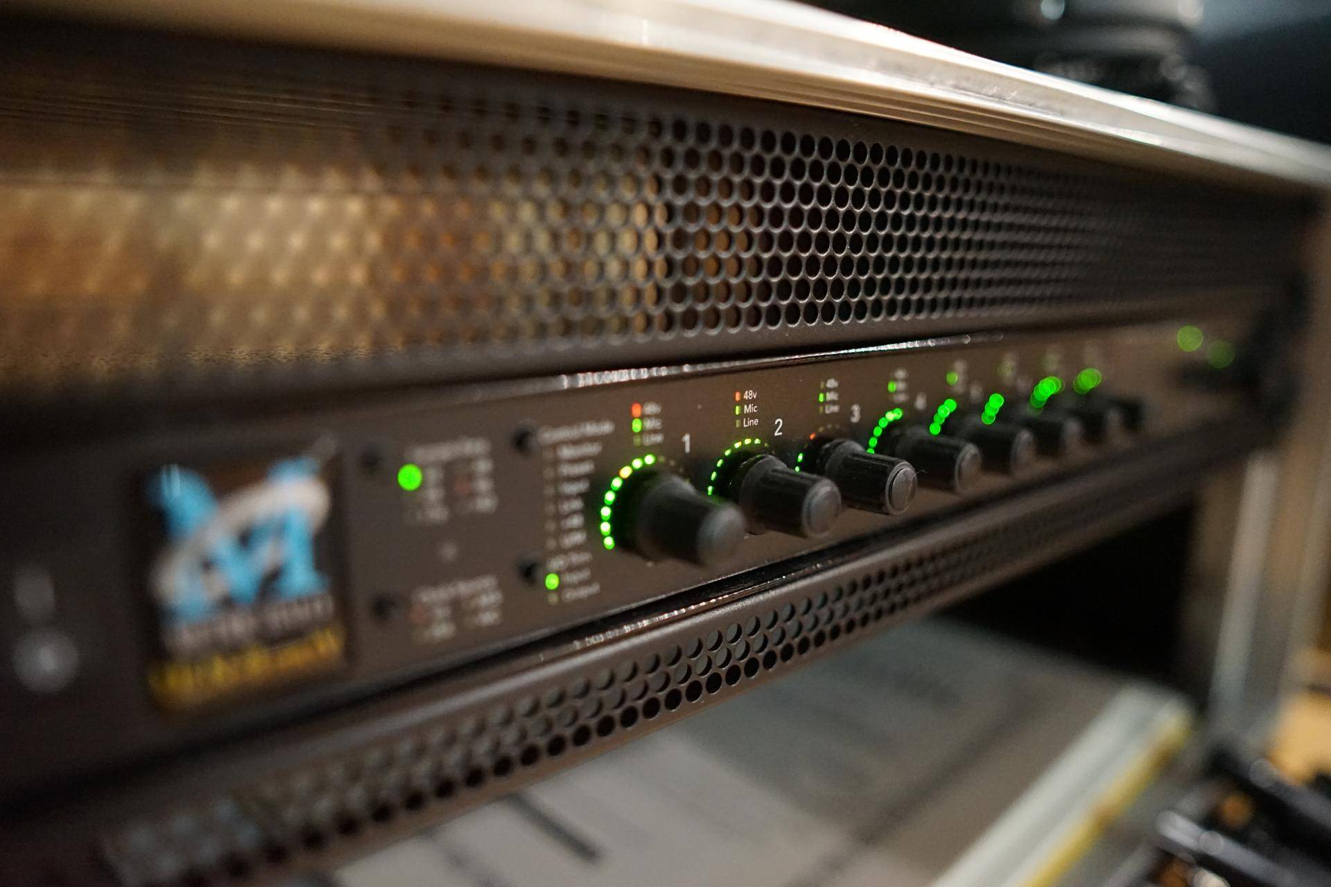 Nahaufnahme eines Audio-Interfaces mit leuchtenden grünen Anzeigen und Reglern für die Klangbearbeitung.