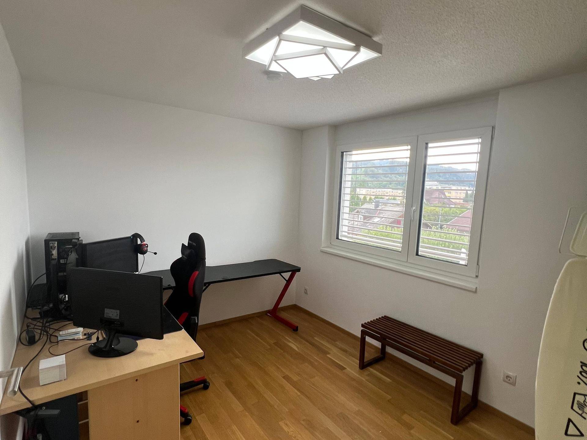 Helles Arbeitszimmer mit Holzboden, Schreibtisch und Blick auf die Umgebung.