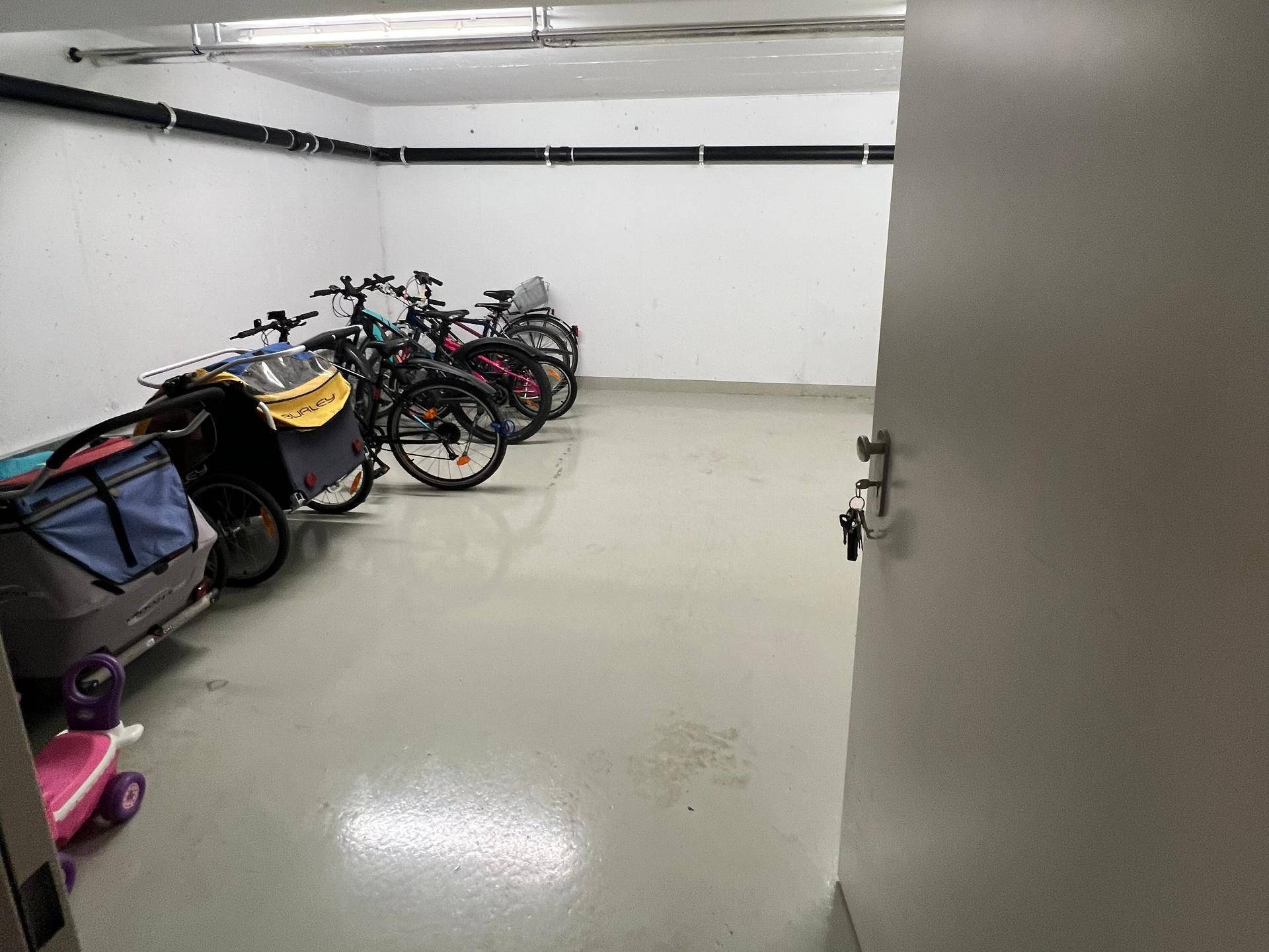 Fahrradraum im Untergeschoss mit mehreren Fahrrädern und Kinderwagen.