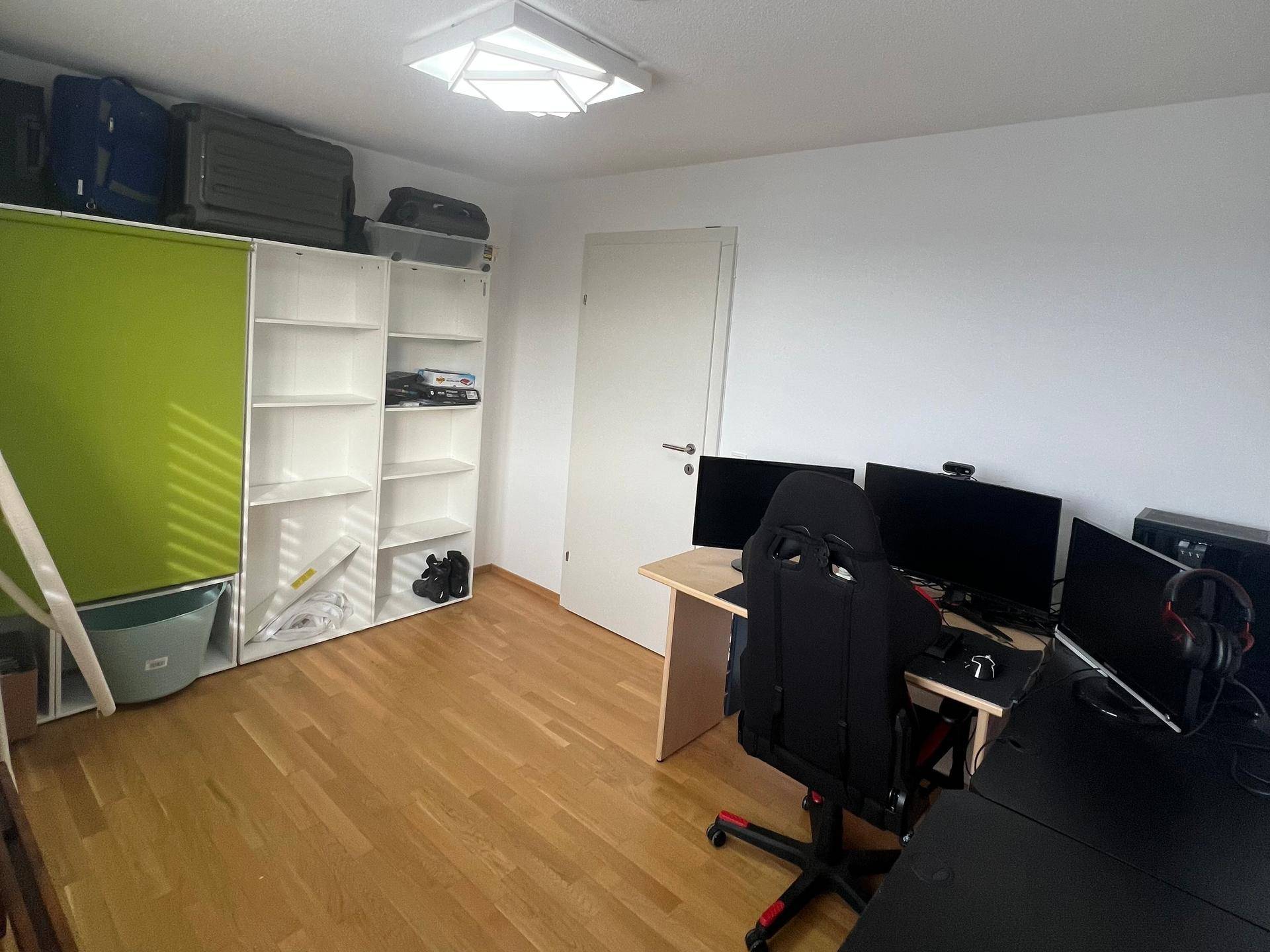 Arbeitszimmer mit Holzboden, Regalen und ausreichend Platz für mehrere Bildschirme.